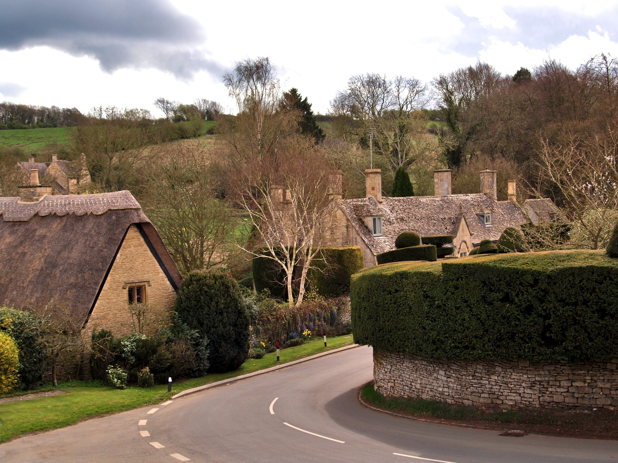 Thatched roof cottages on a winding road in the United Kingdom HD Wallpaper