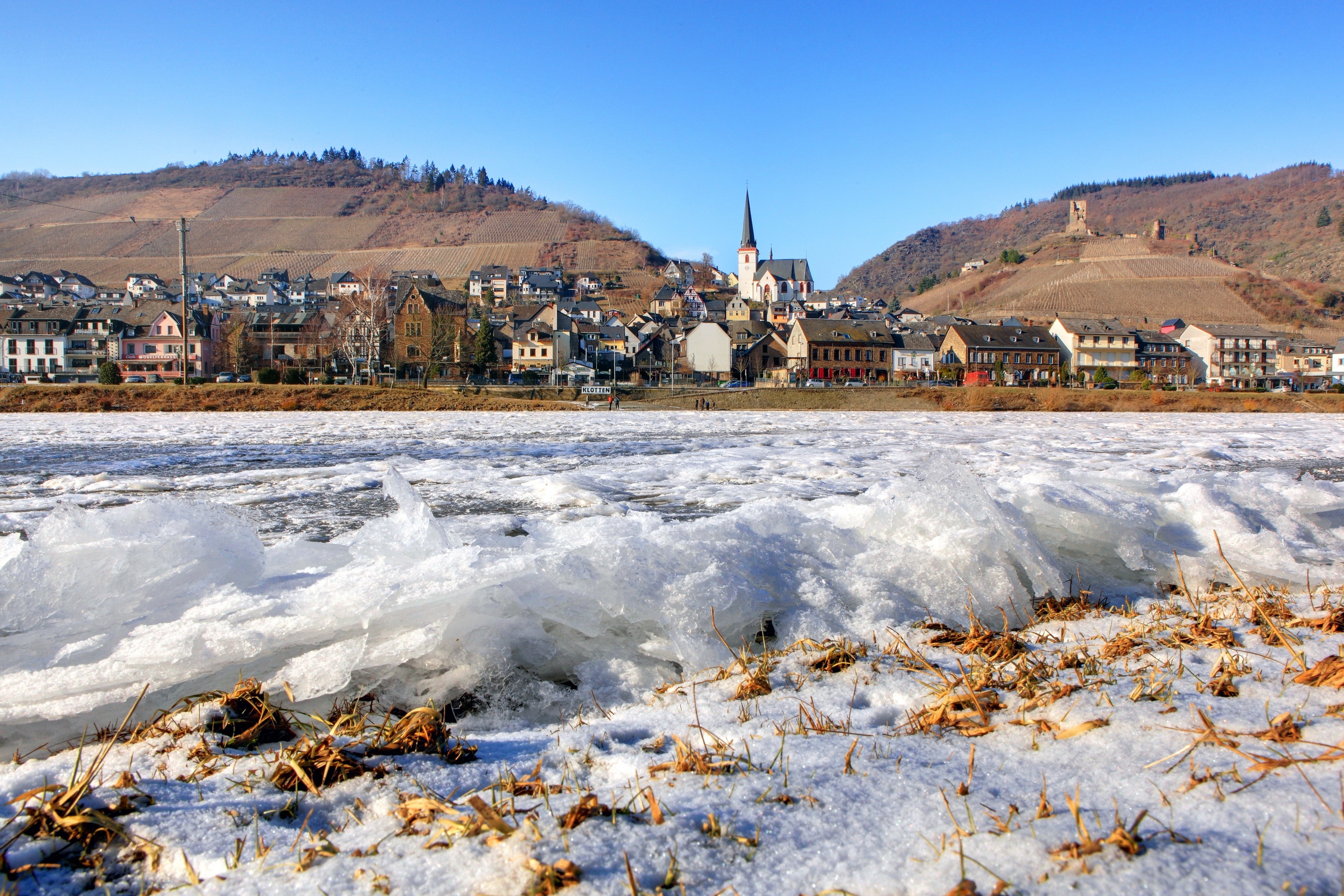 Frozen river in front of a German town with vineyards and castle ruins HD Wallpaper
