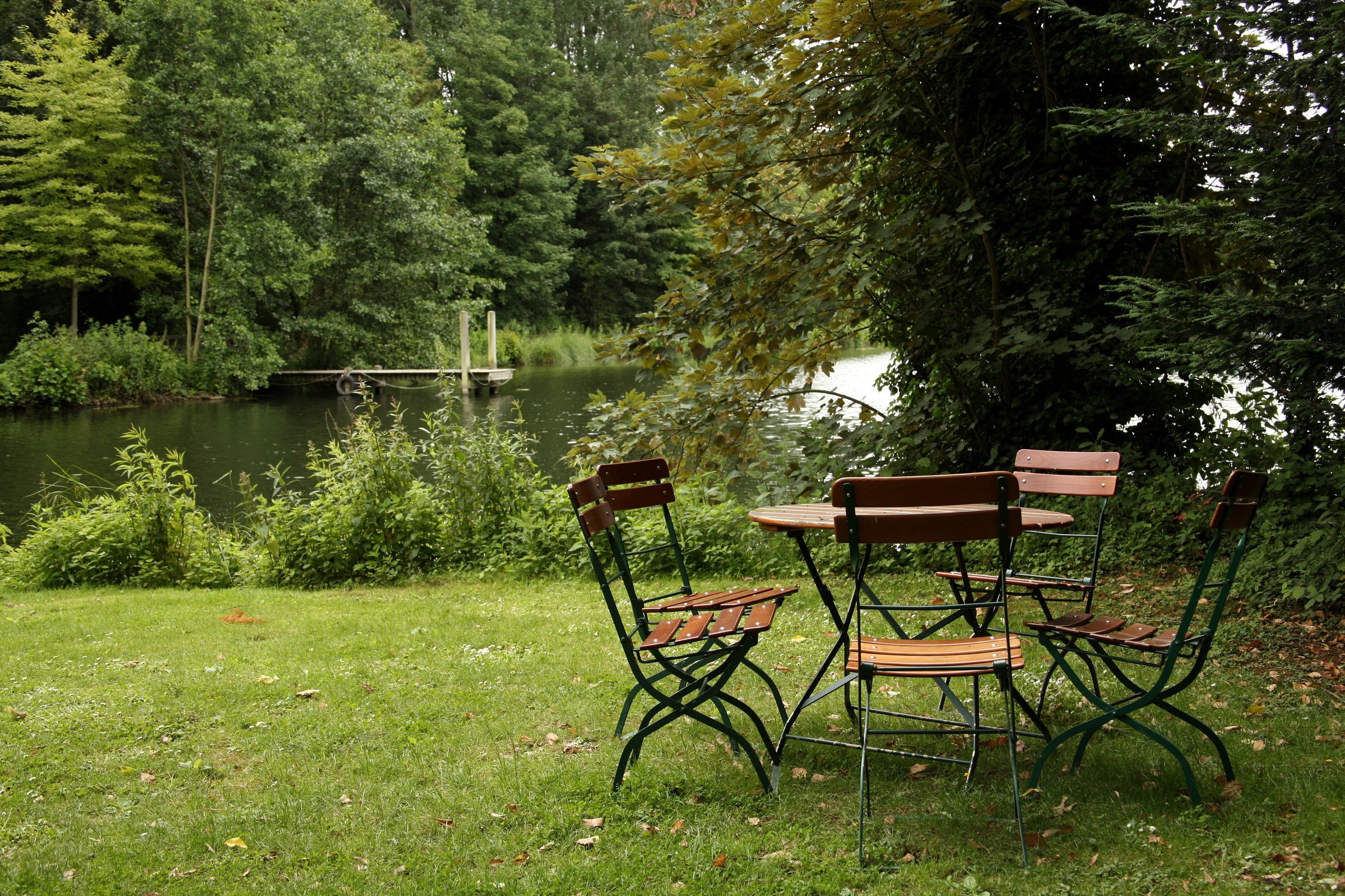 Outdoor table and chairs by a lake HD Wallpaper