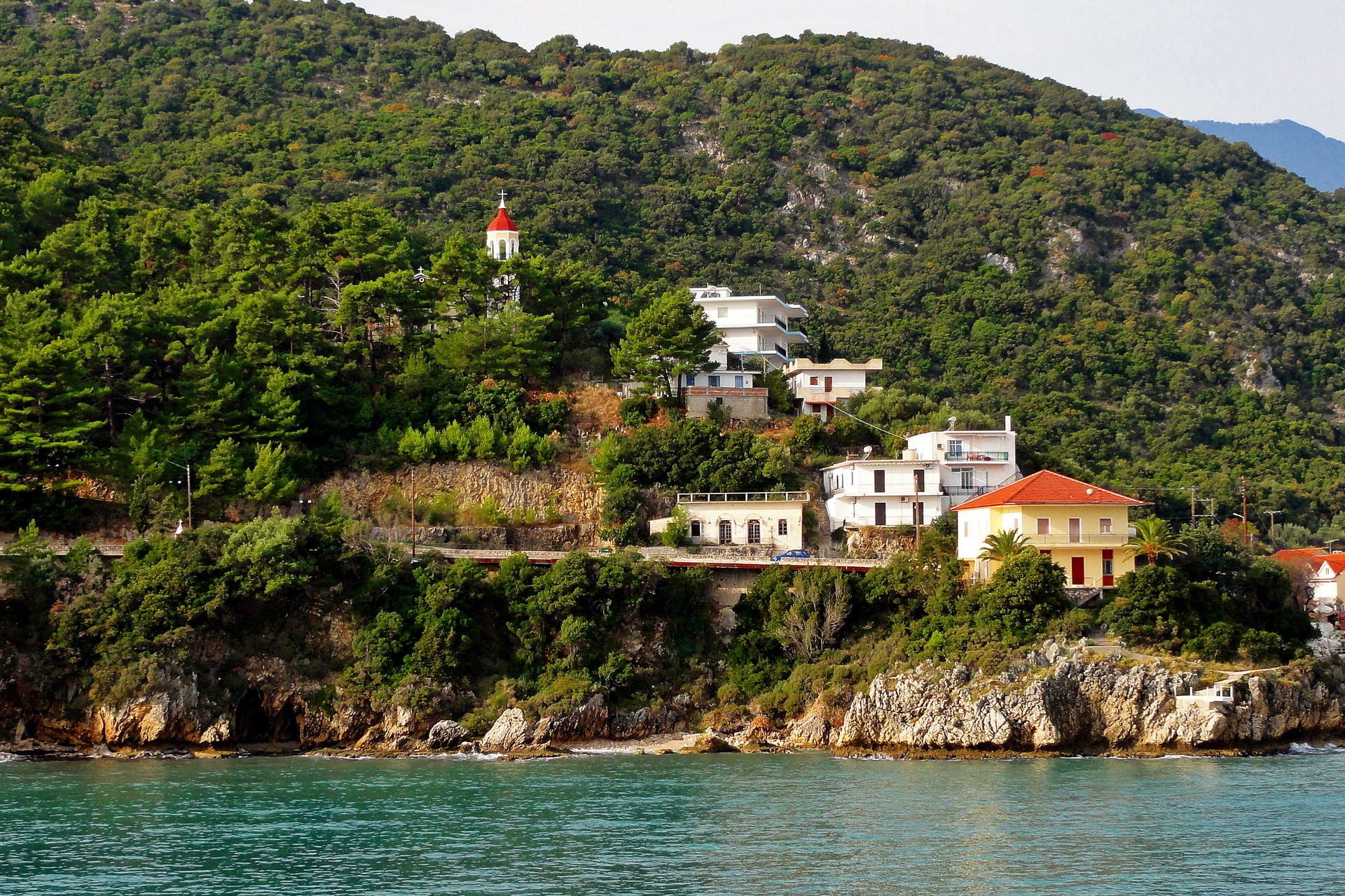 Houses and church on a green hillside by the sea in Poros, Kefalonia, Greece HD Wallpaper