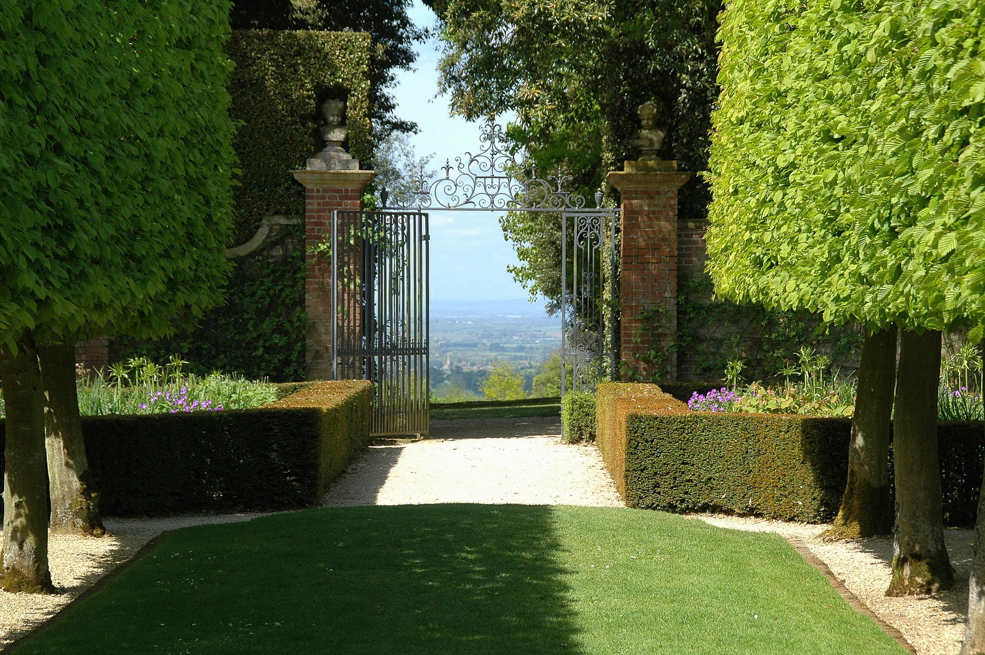 Formal garden with ornate gate and distant view HD Wallpaper