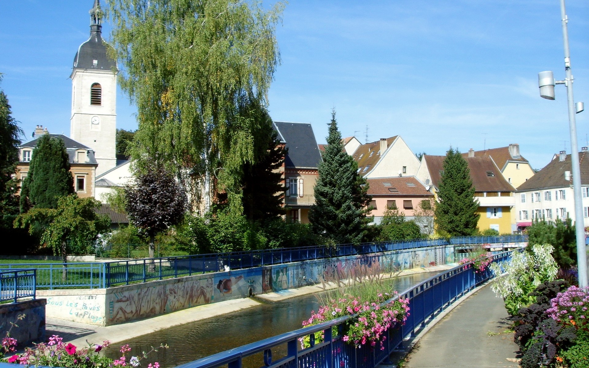 Riverfront with church tower in a French town HD Wallpaper