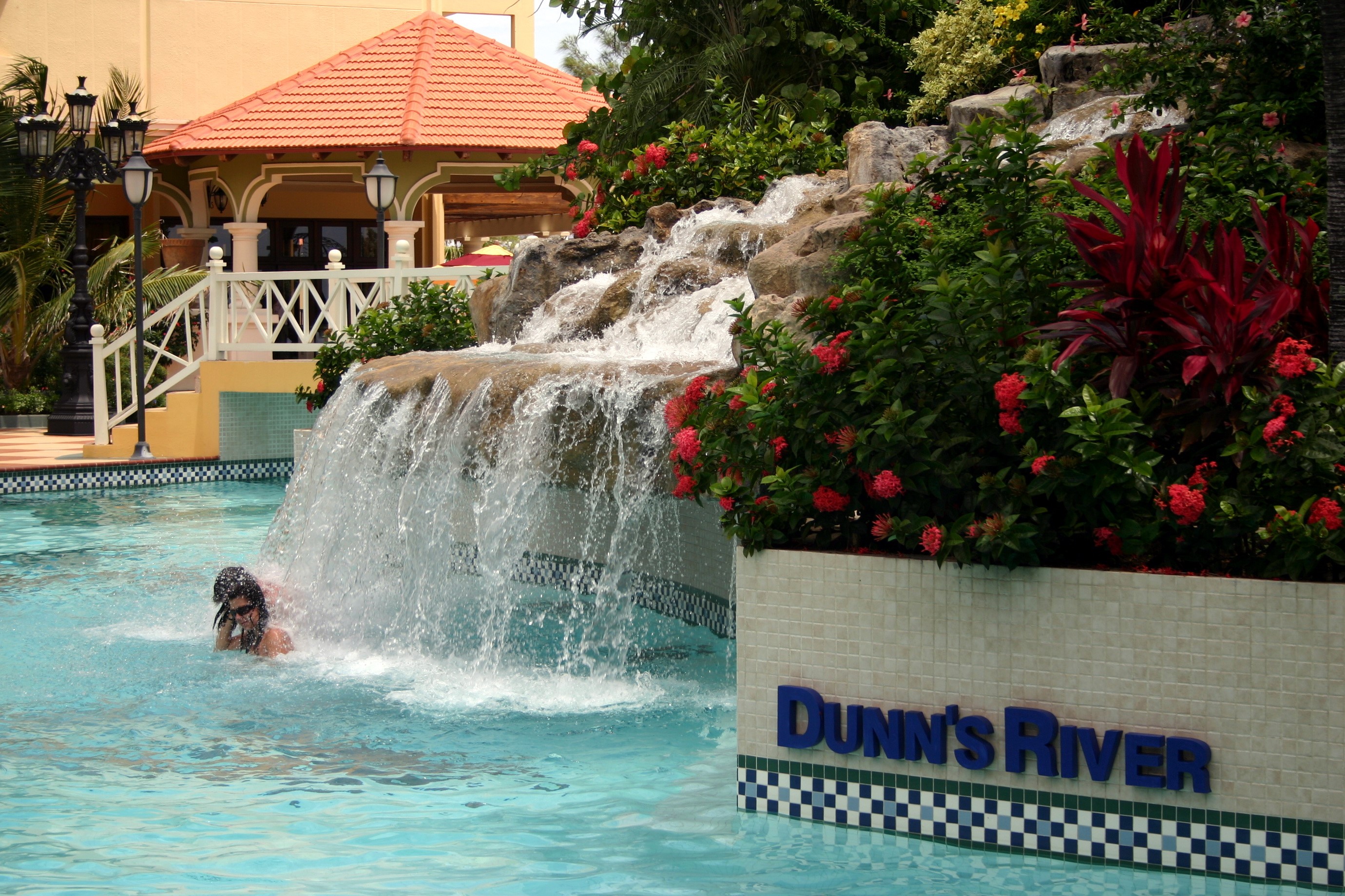 Person swimming under waterfall at Dunn's River HD Wallpaper