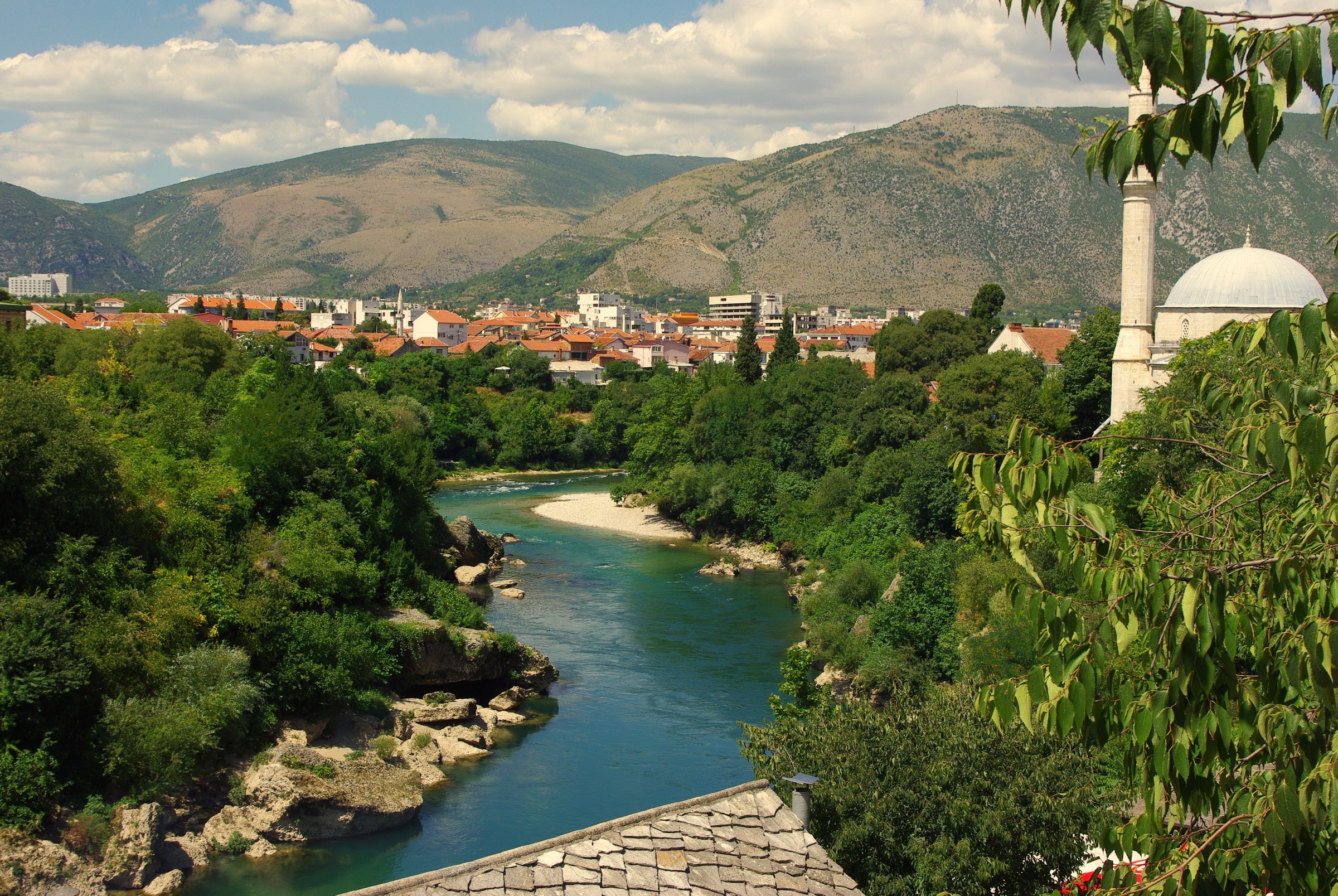 River flowing through a town with a mosque and mountains HD Wallpaper