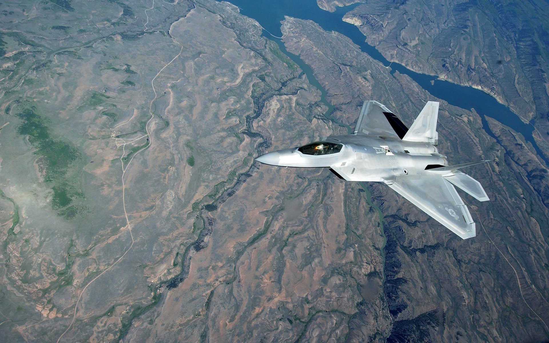 F-22 Raptor fighter jet flying over a canyon HD Wallpaper