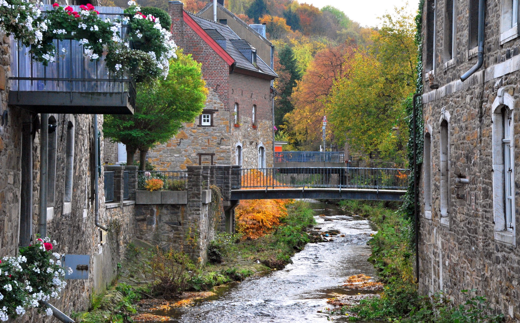 Stone houses and a stream in a German village during autumn HD Wallpaper