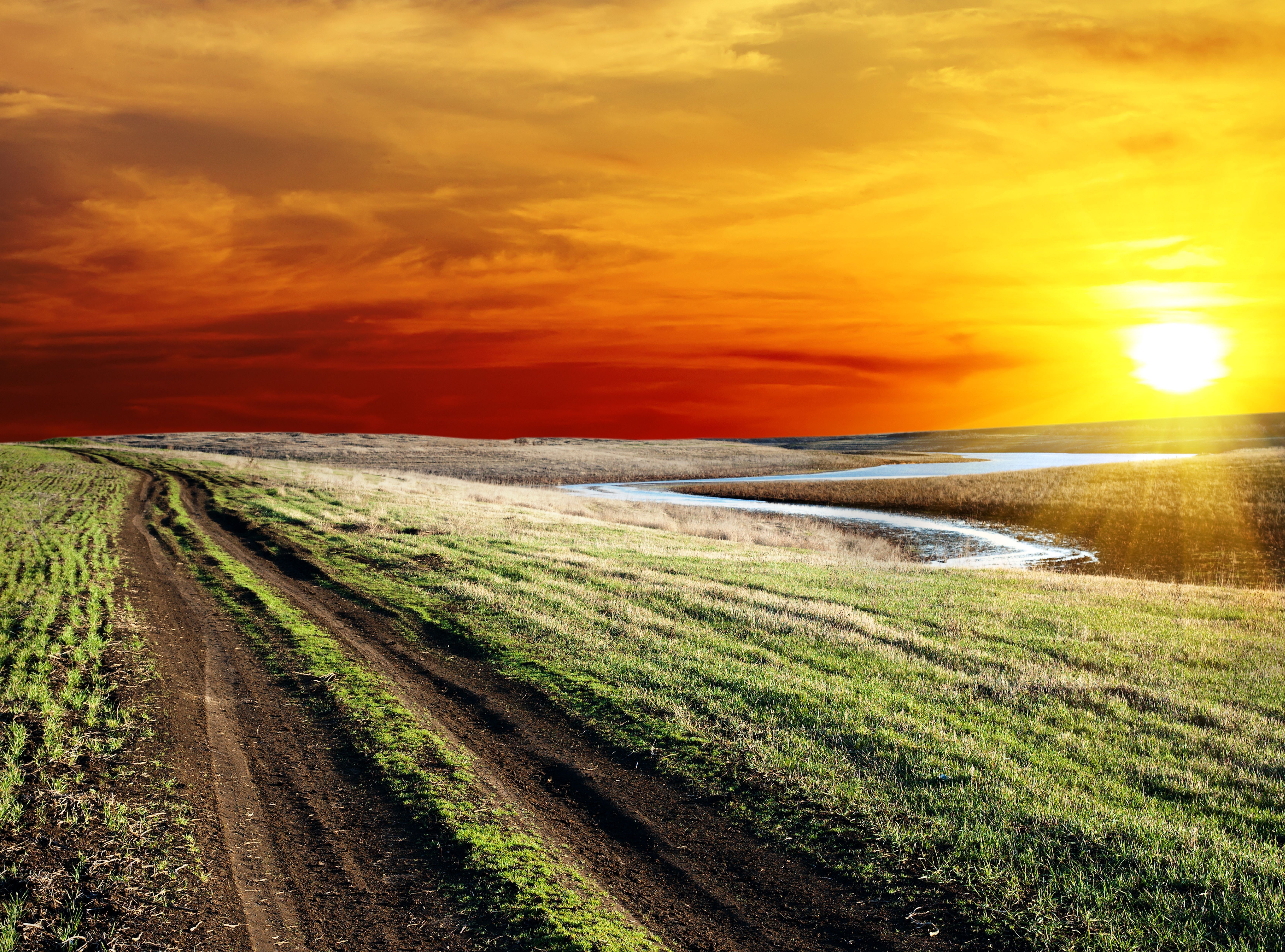 Sunset over a winding dirt road and river HD Wallpaper