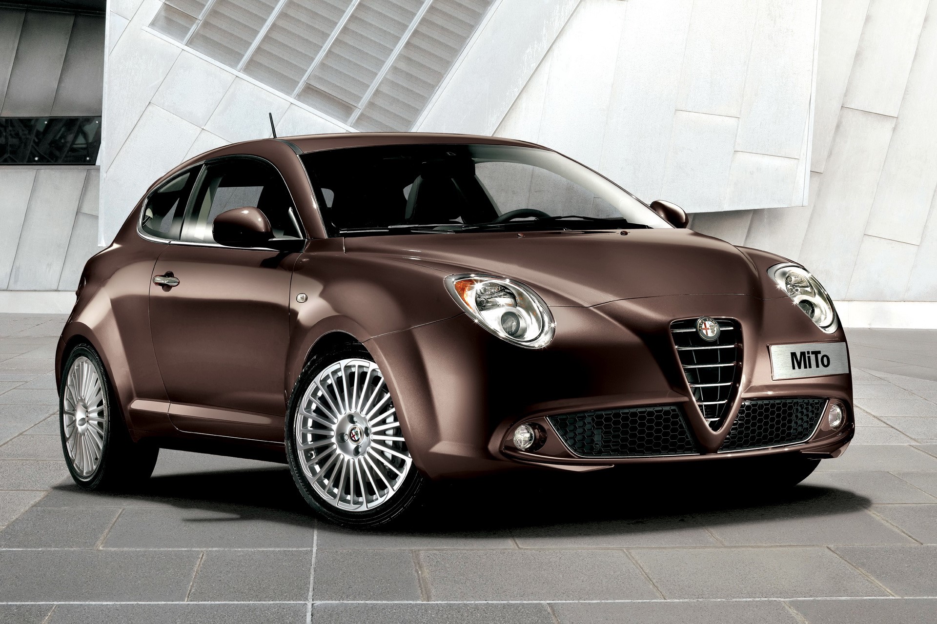 Brown Alfa Romeo MiTo parked in front of a modern building HD Wallpaper