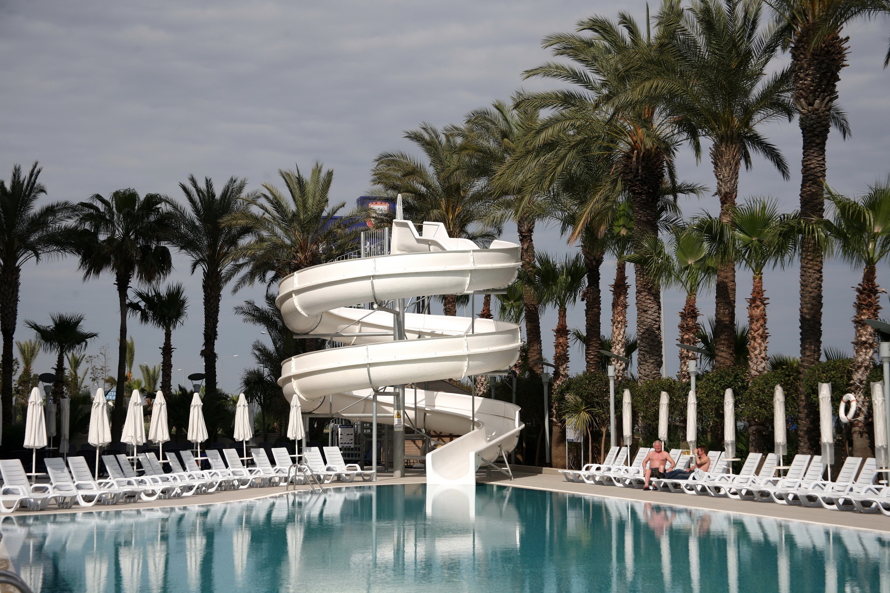Resort pool with water slide and palm trees HD Wallpaper
