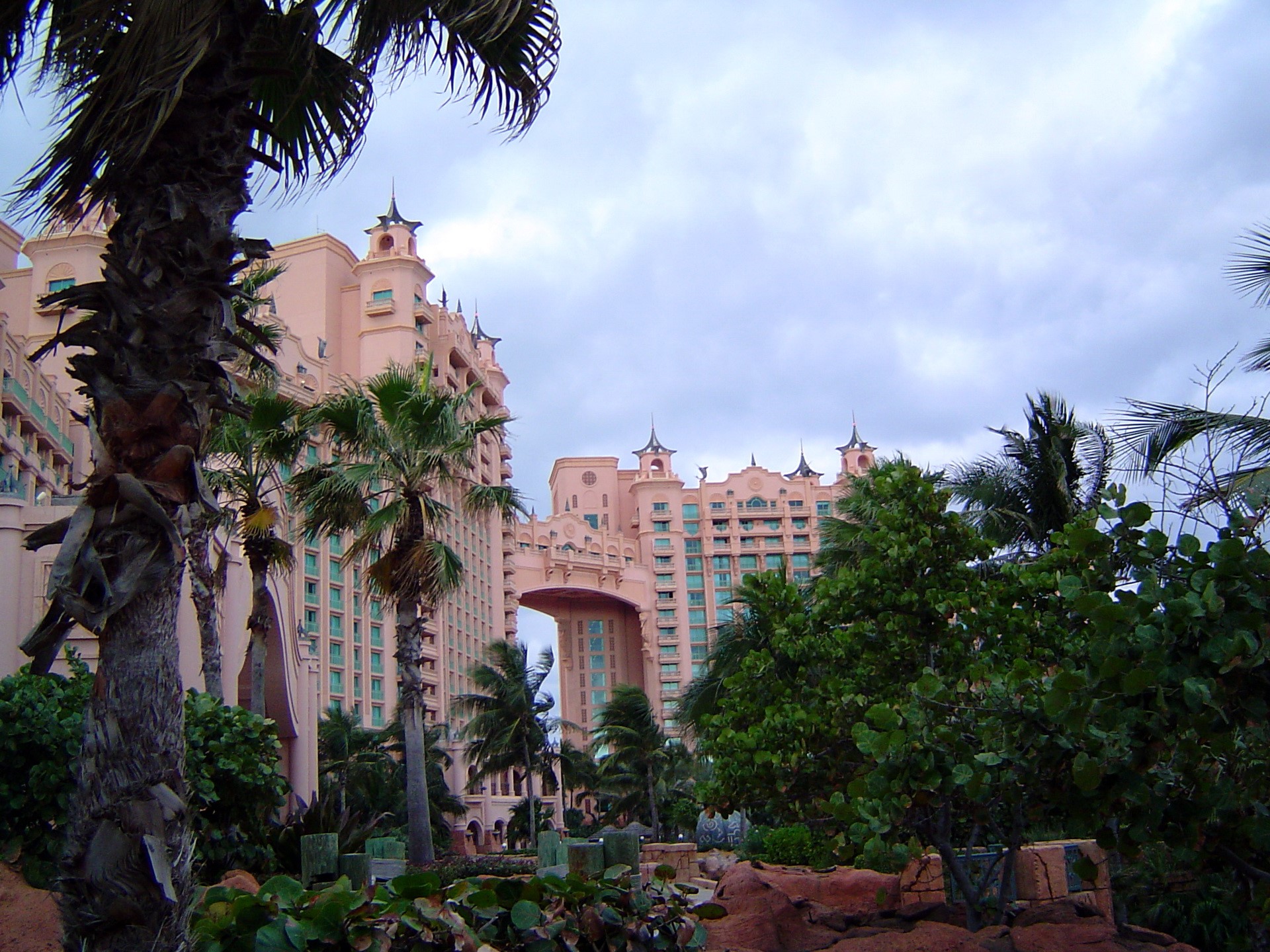 Pink resort building with palm trees and cloudy sky HD Wallpaper