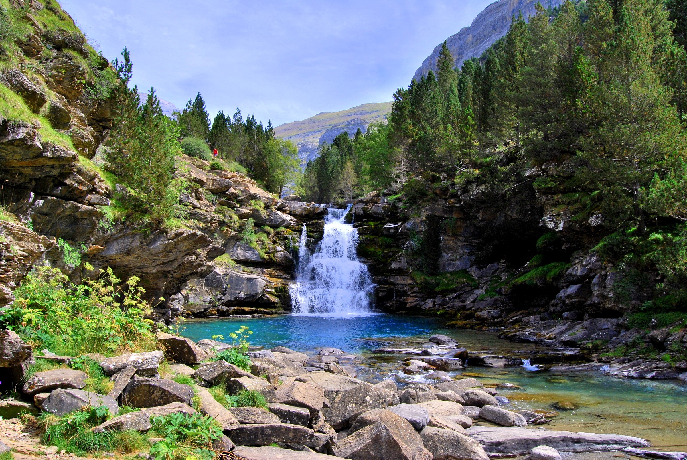 Waterfall cascading into a turquoise pool in a rocky gorge HD Wallpaper