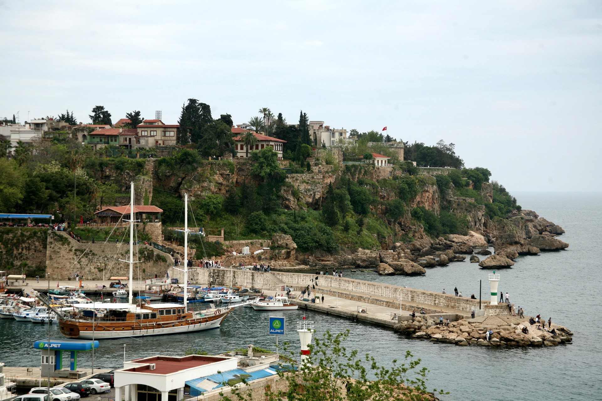 Harbor with boats and cliffside buildings in Turkey HD Wallpaper