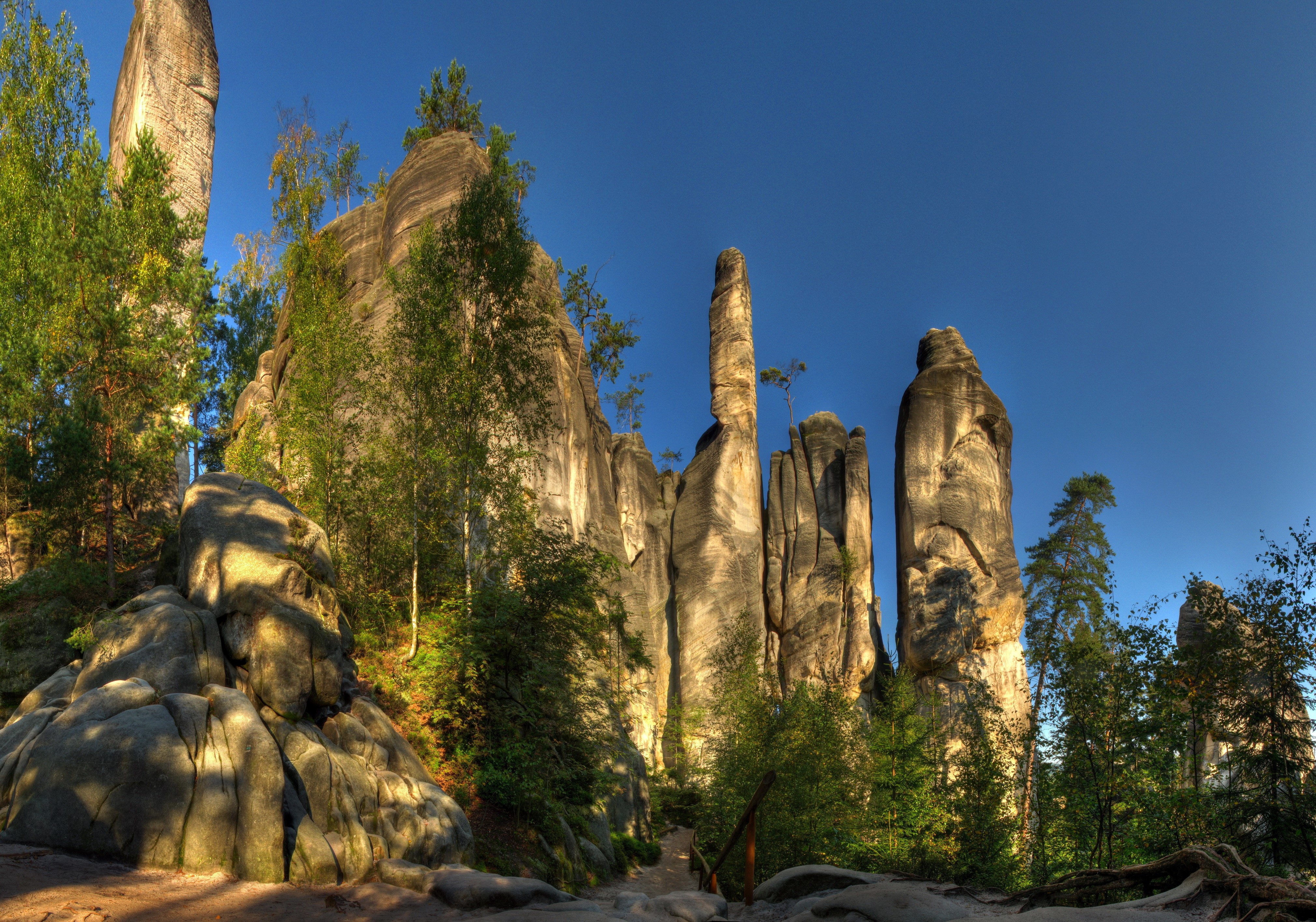 Rock formations and trees under a blue sky HD Wallpaper