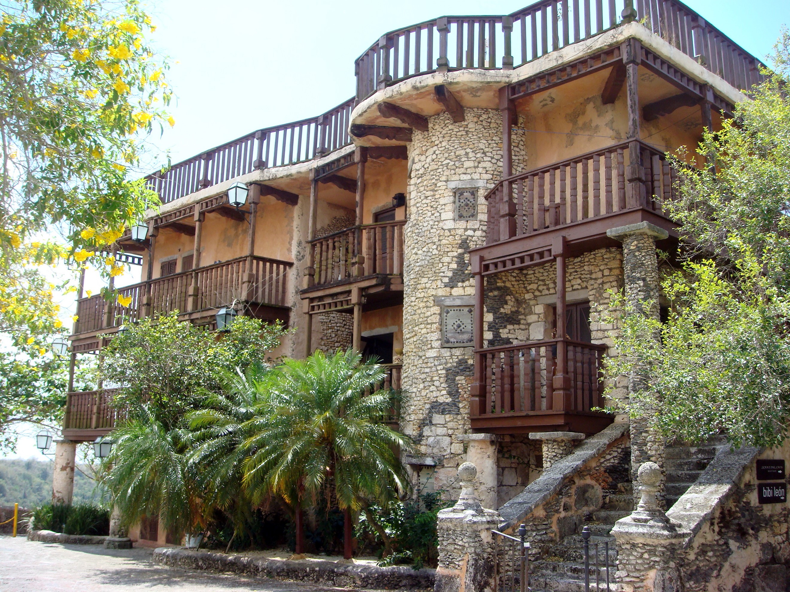 Stone building with wooden balconies and palm trees HD Wallpaper