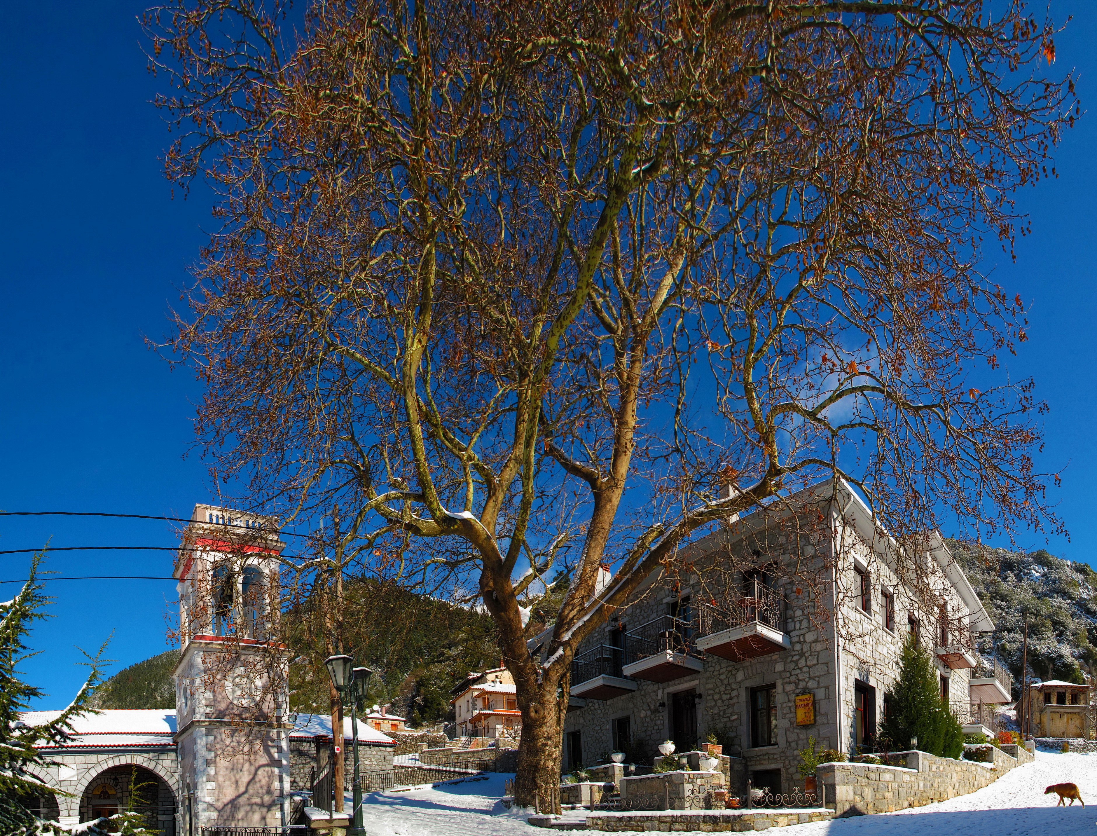 Stone houses and bell tower in a snowy Greek village HD Wallpaper