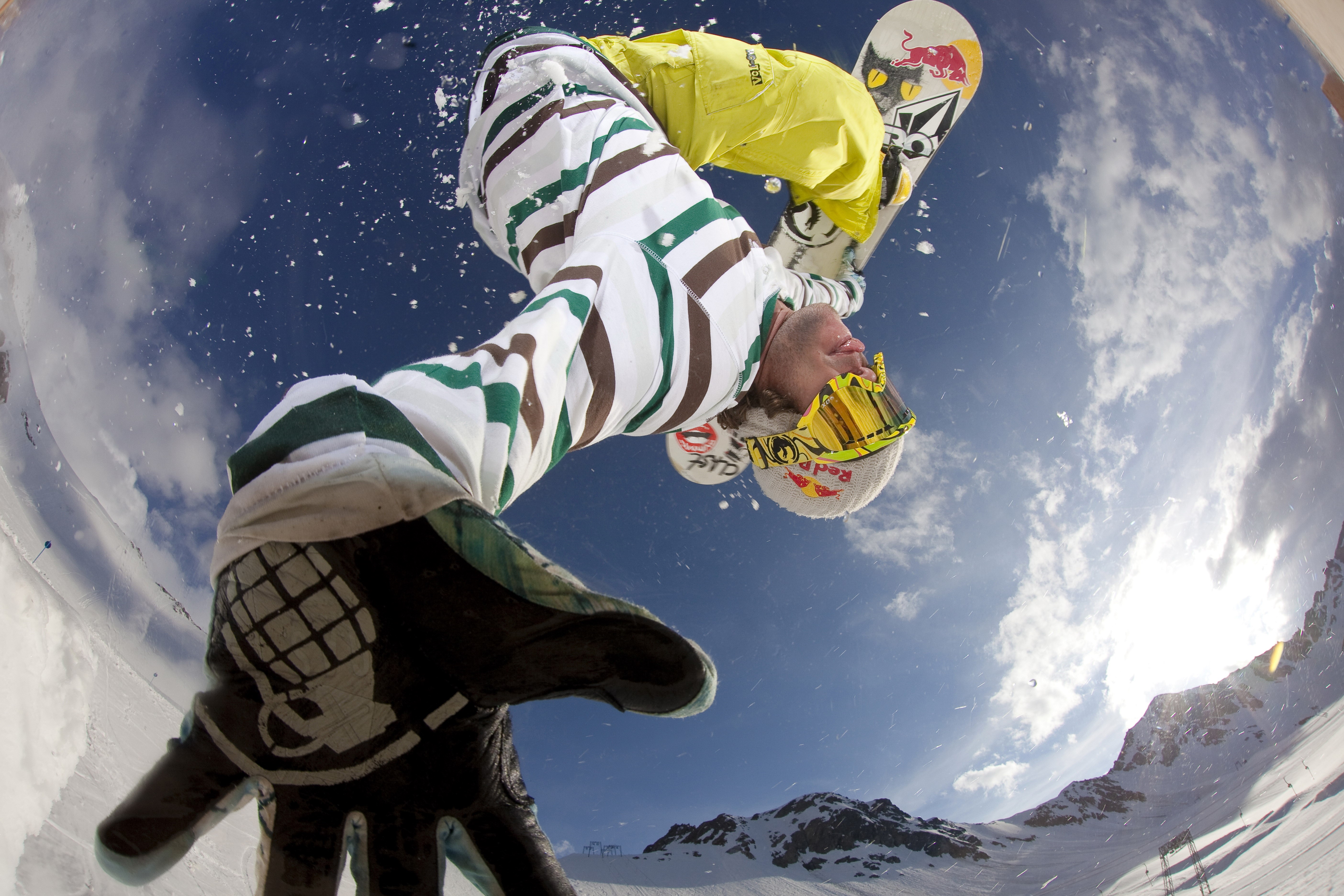 Snowboarder performing a trick against a blue sky HD Wallpaper