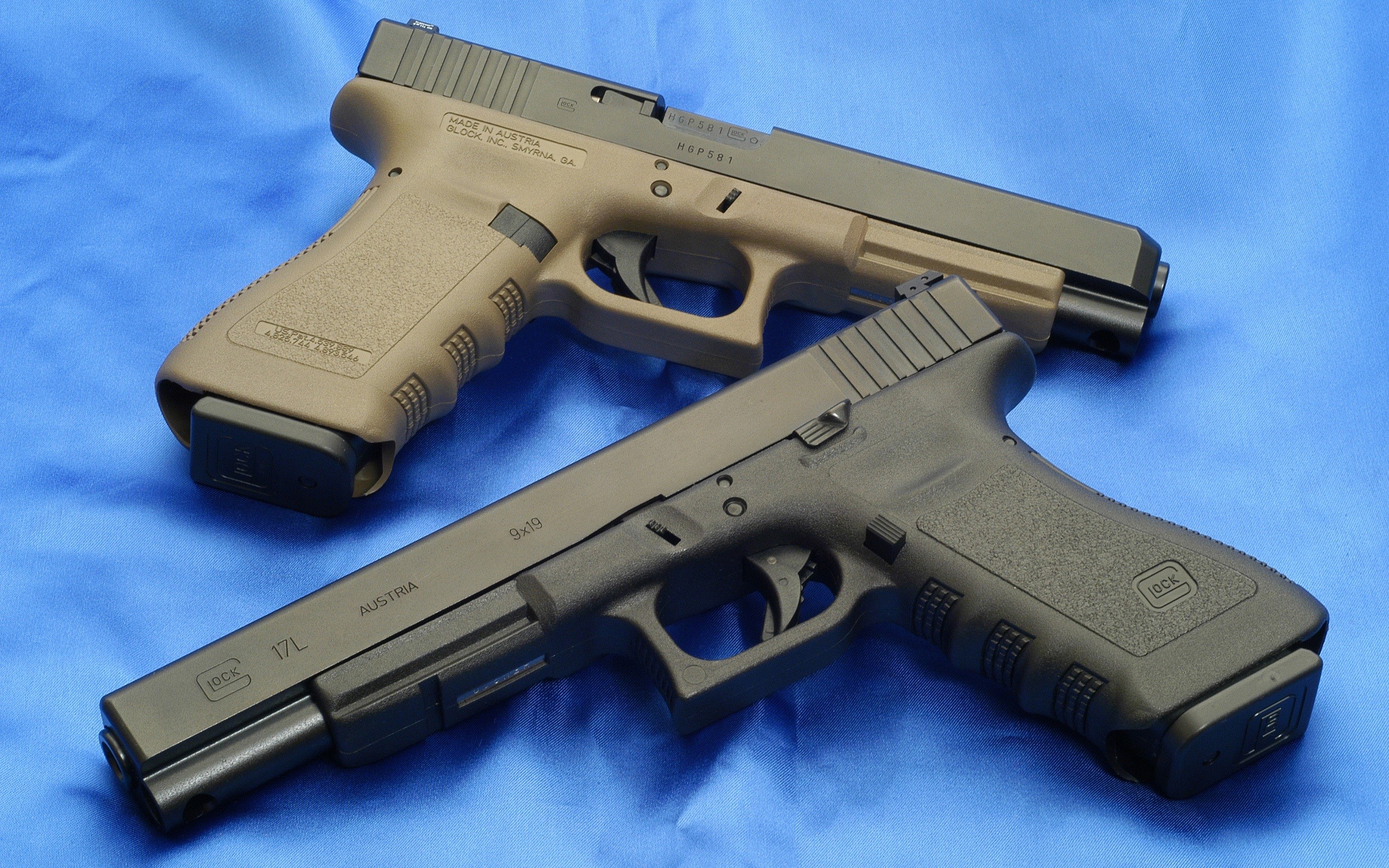 Two Glock pistols on a blue surface HD Wallpaper