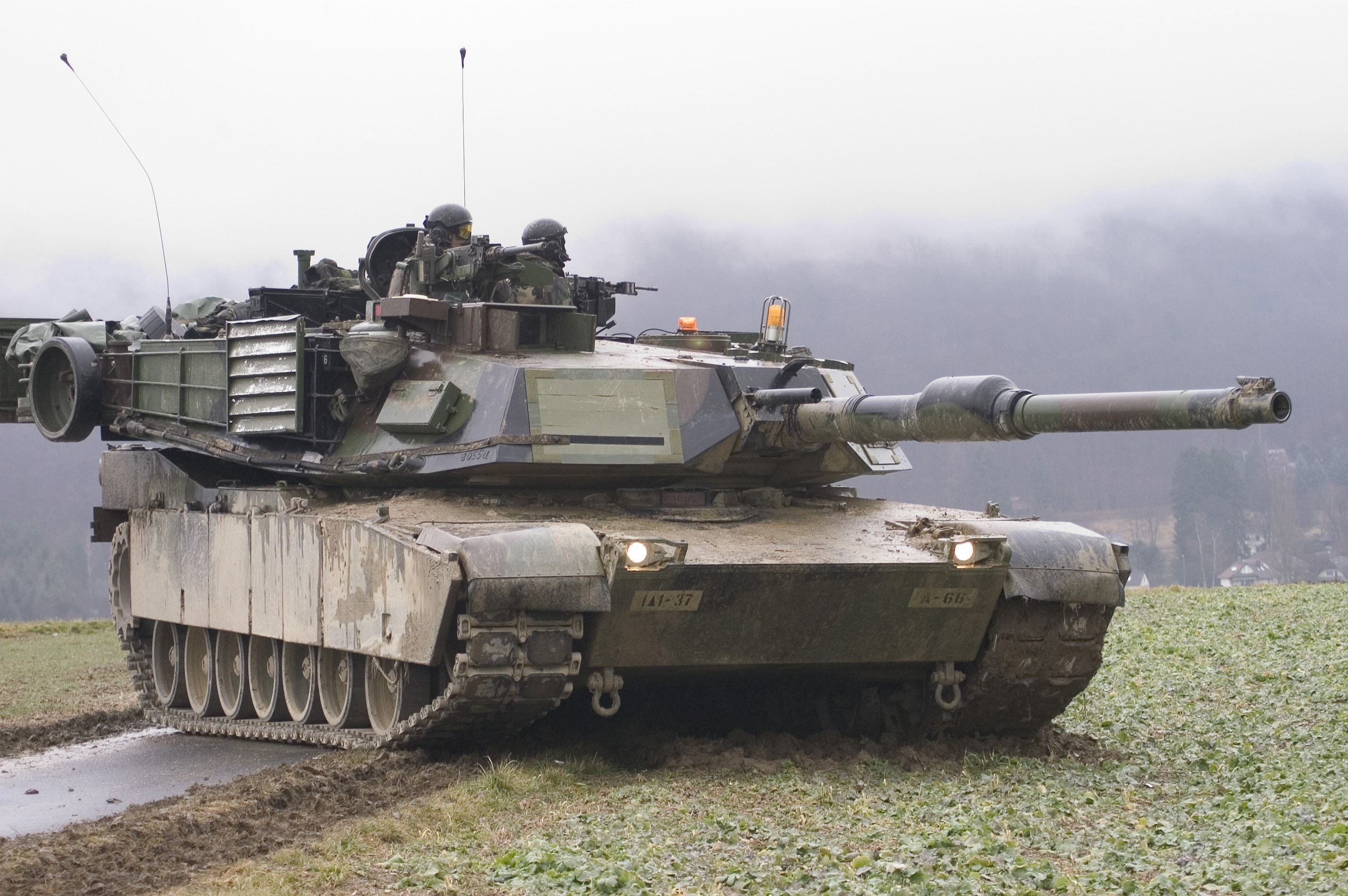 M1 Abrams tank with crew in muddy field HD Wallpaper
