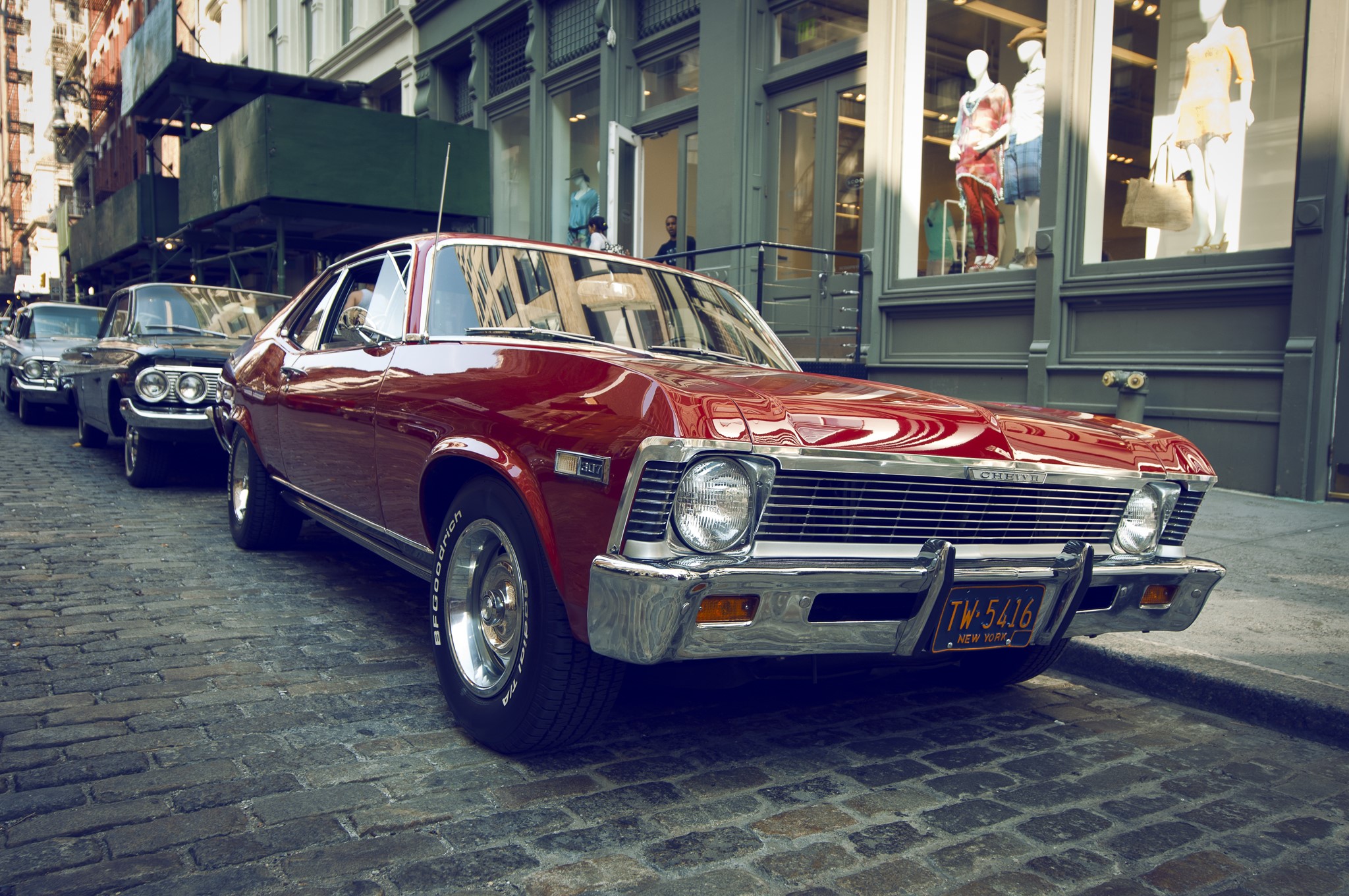 Red Chevrolet Nova parked on cobblestone street HD Wallpaper