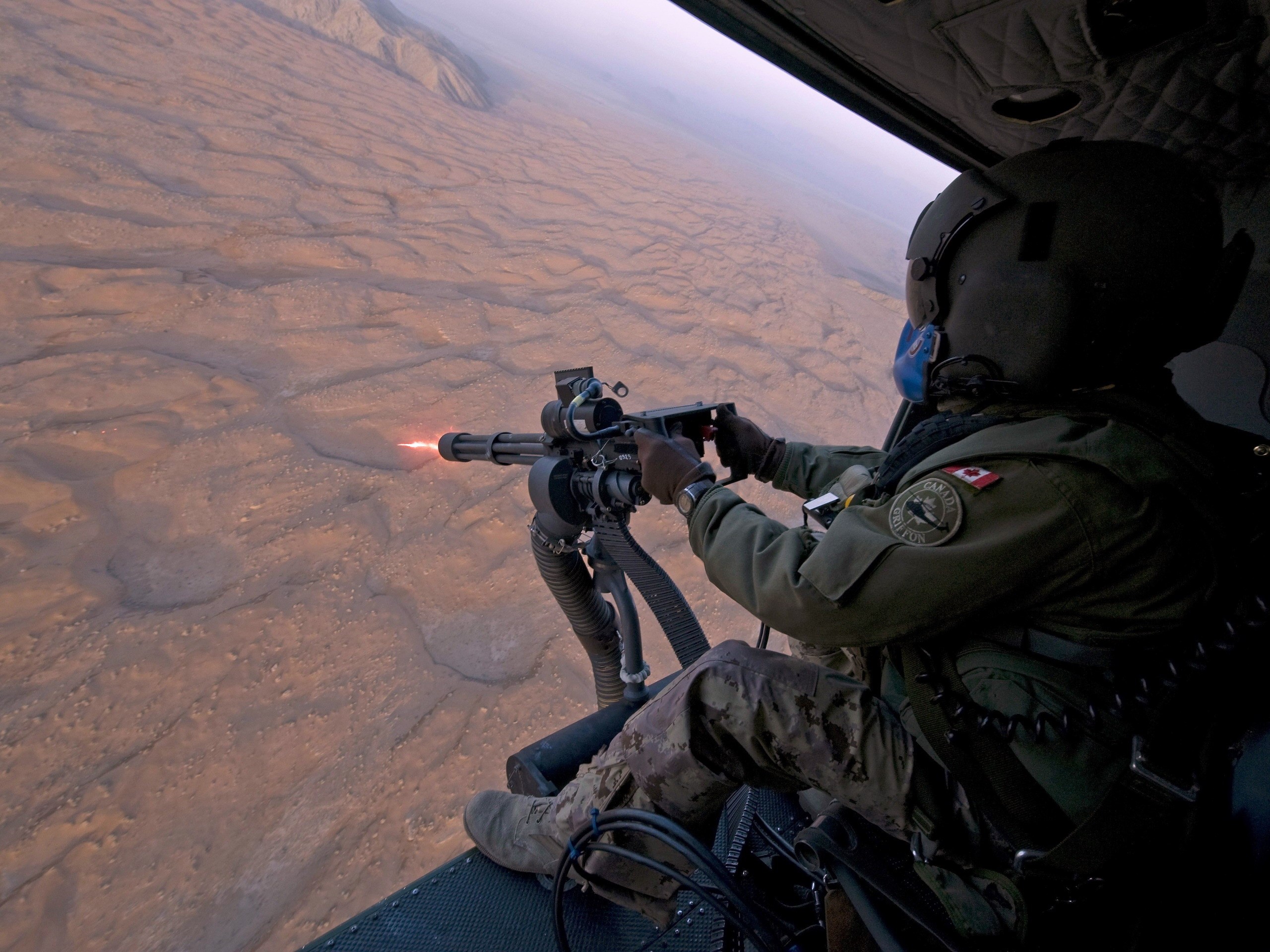 Soldier firing a minigun from a helicopter HD Wallpaper