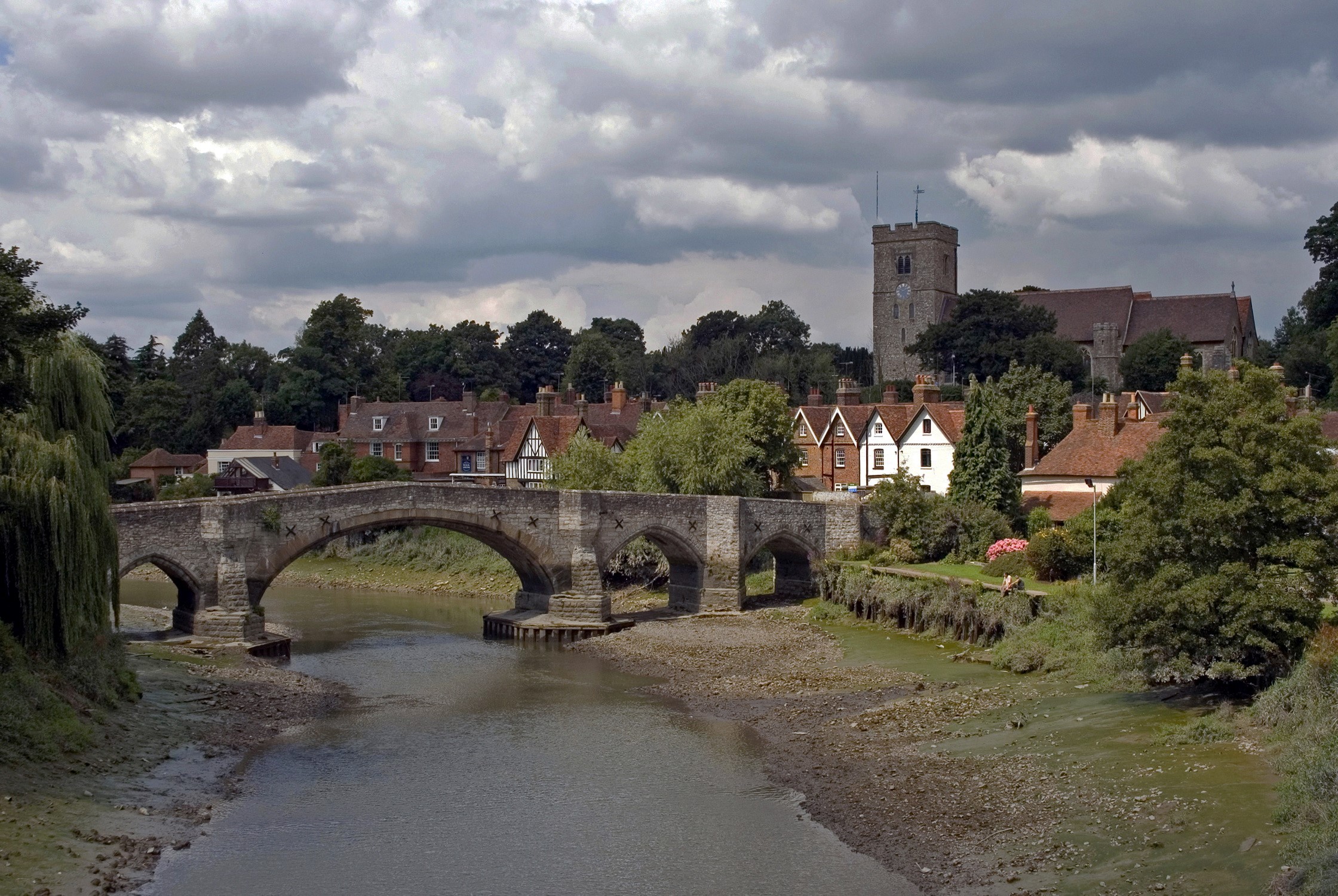 Stone bridge over a river in a village with a church HD Wallpaper