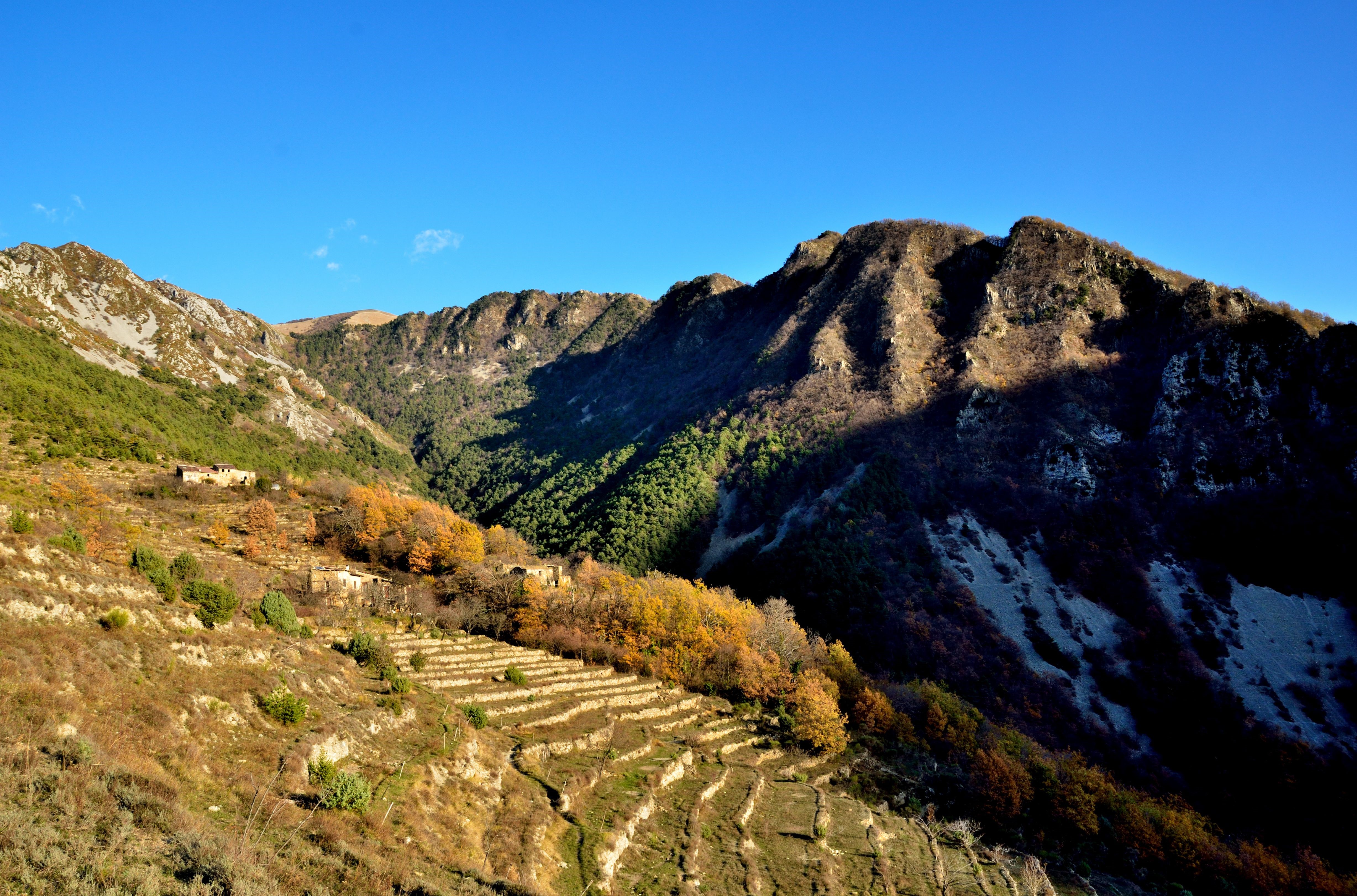 Terraced fields on a mountainside with abandoned buildings HD Wallpaper