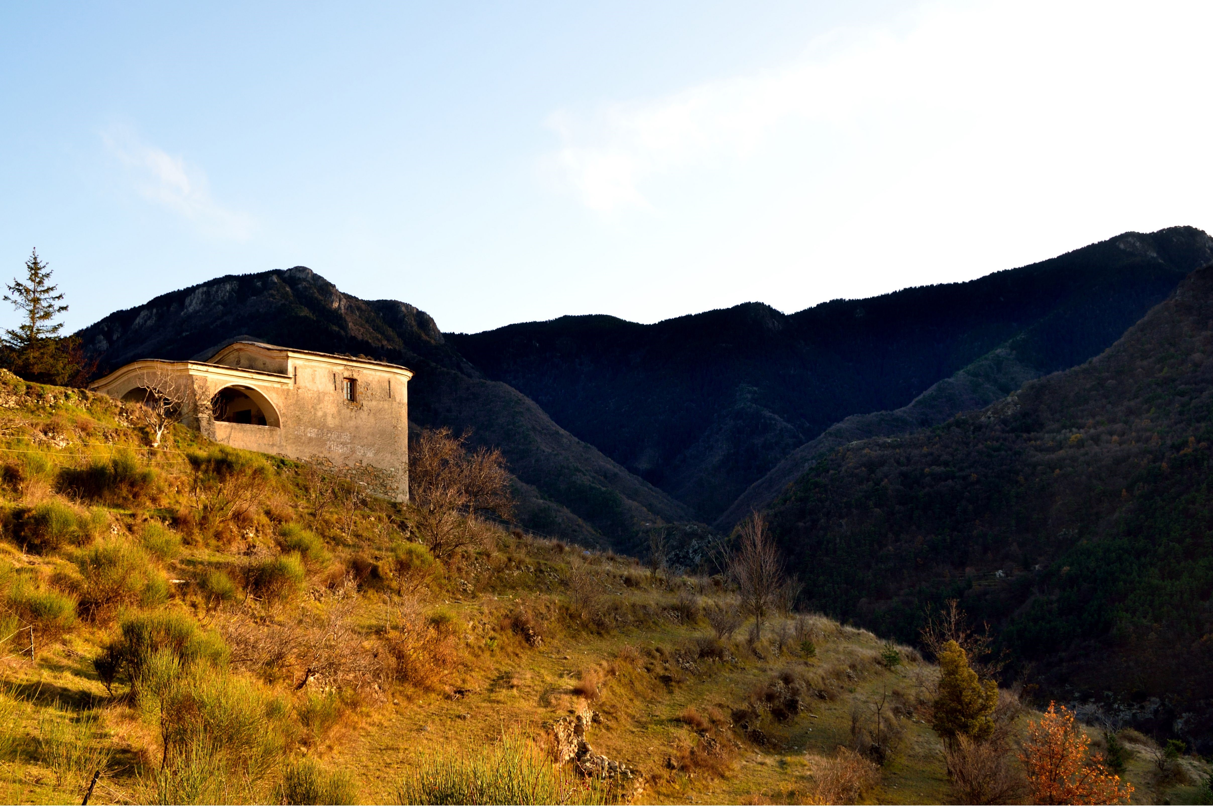 Abandoned building on a grassy hillside with mountains HD Wallpaper