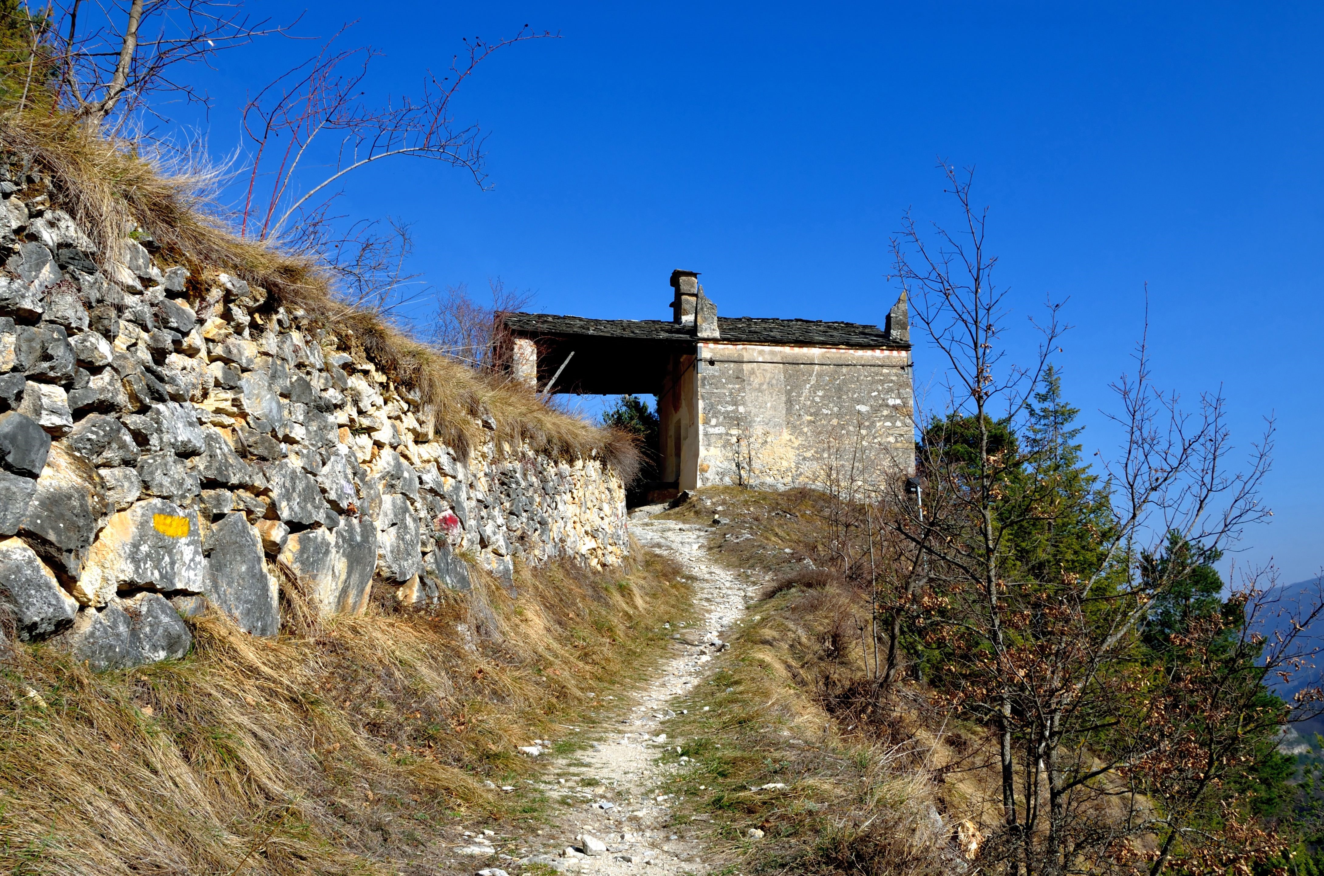 Stone wall and path leading to old building in Italy HD Wallpaper