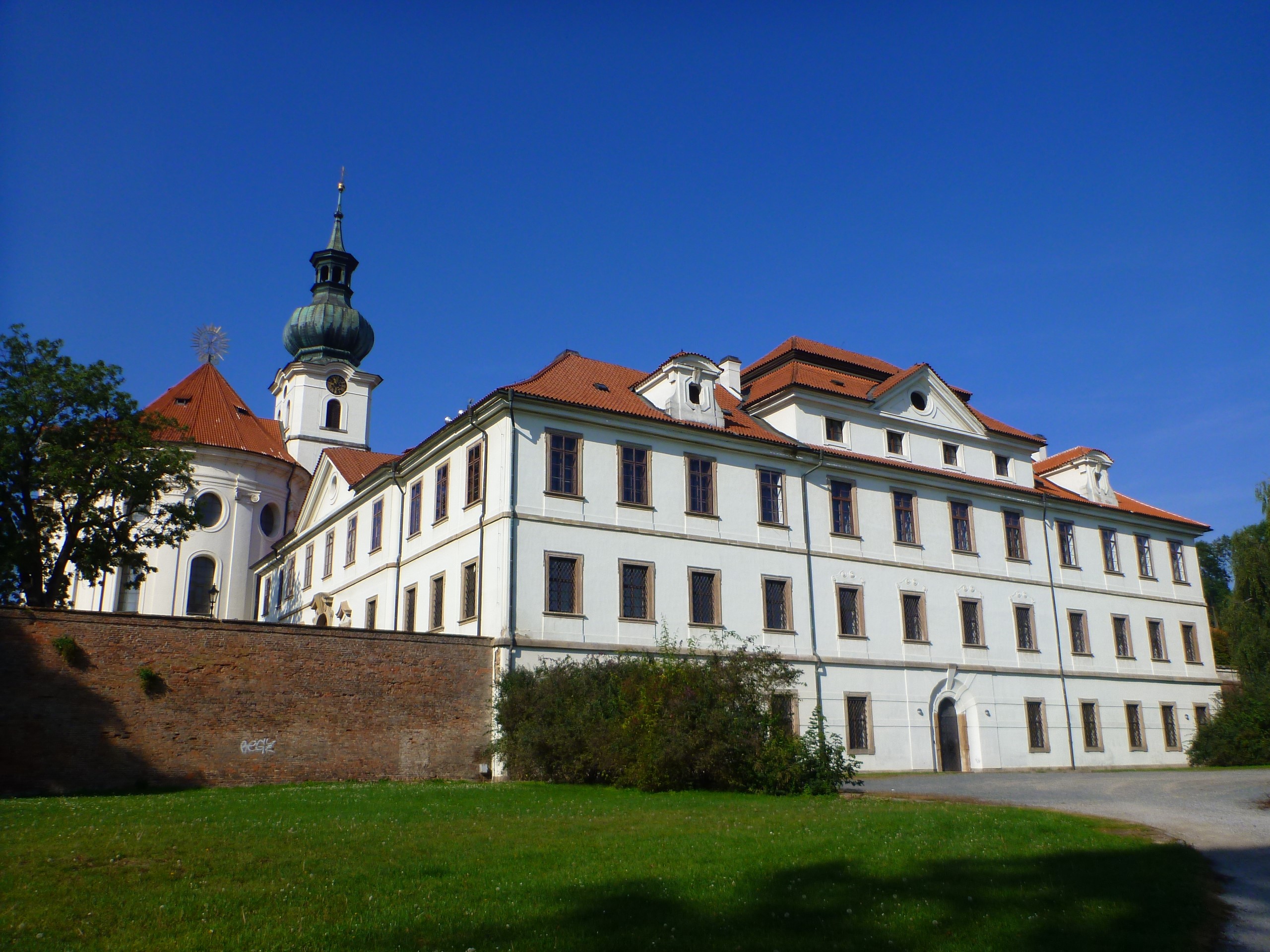 White monastery building with a green dome tower and red roof under a blue sky. HD Wallpaper