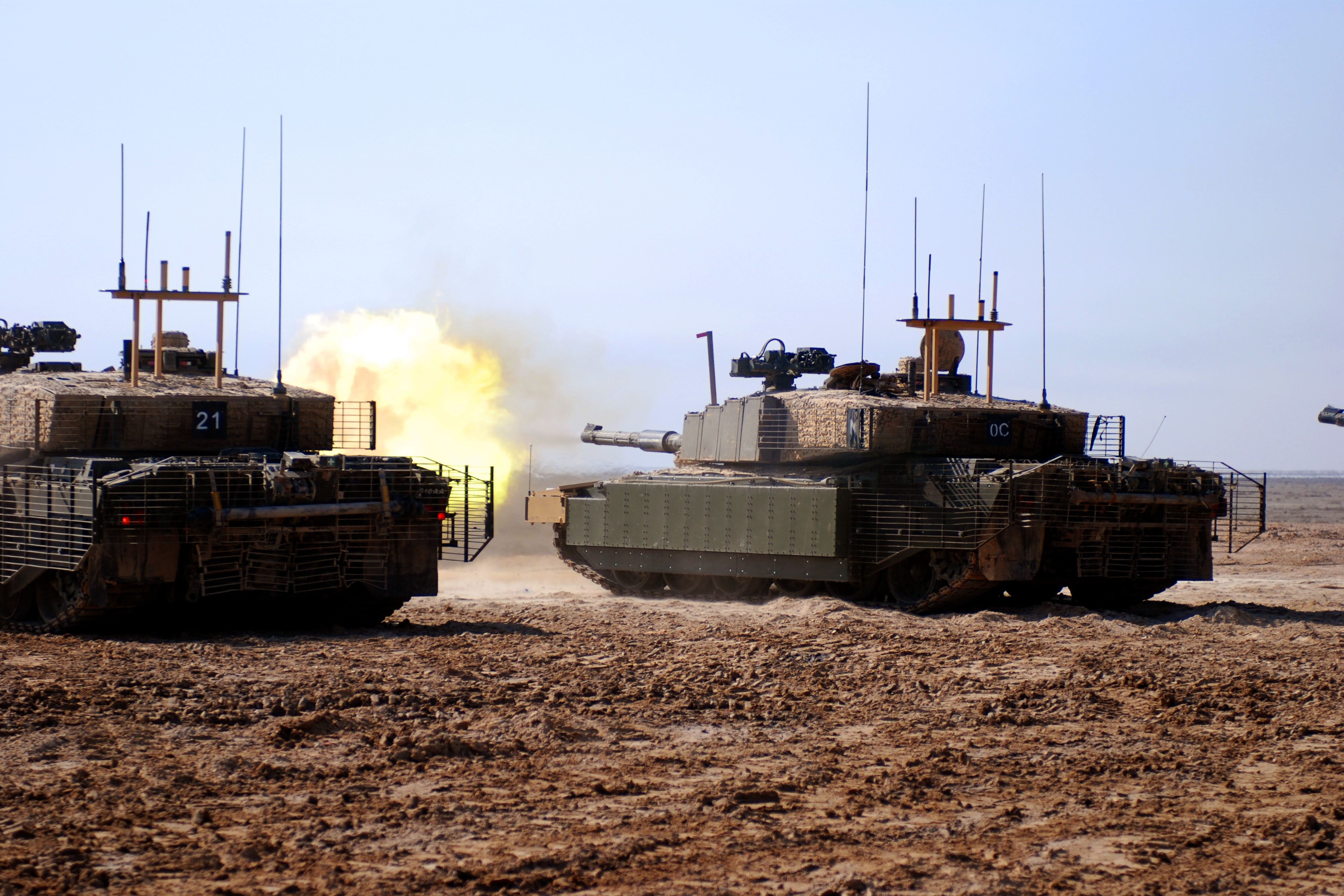 Two tanks firing in a desert landscape HD Wallpaper