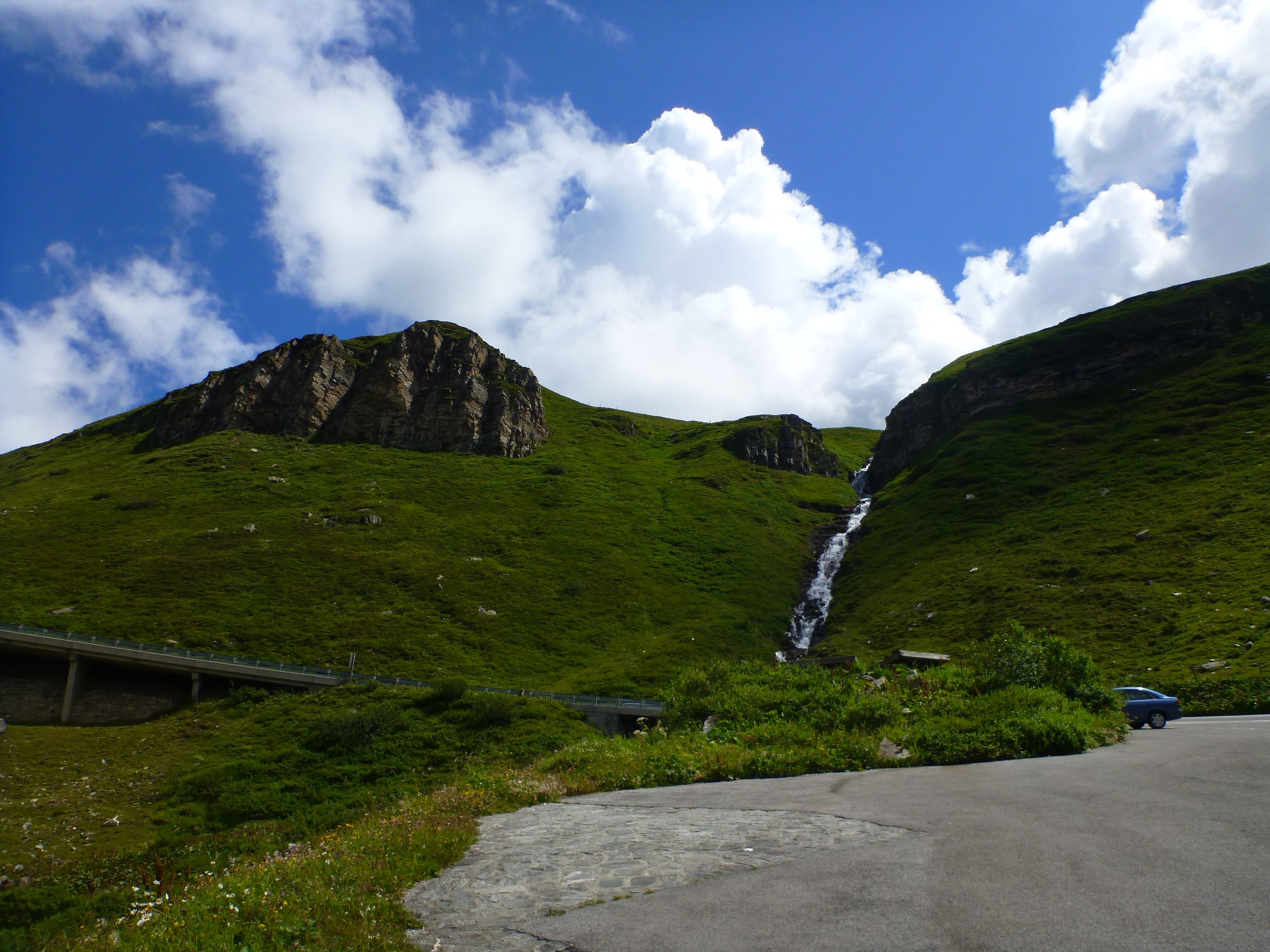 Mountain landscape with a waterfall and a road HD Wallpaper