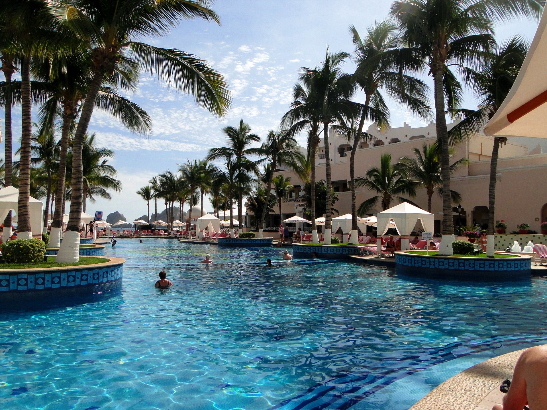 Resort pool with palm trees and cabanas HD Wallpaper