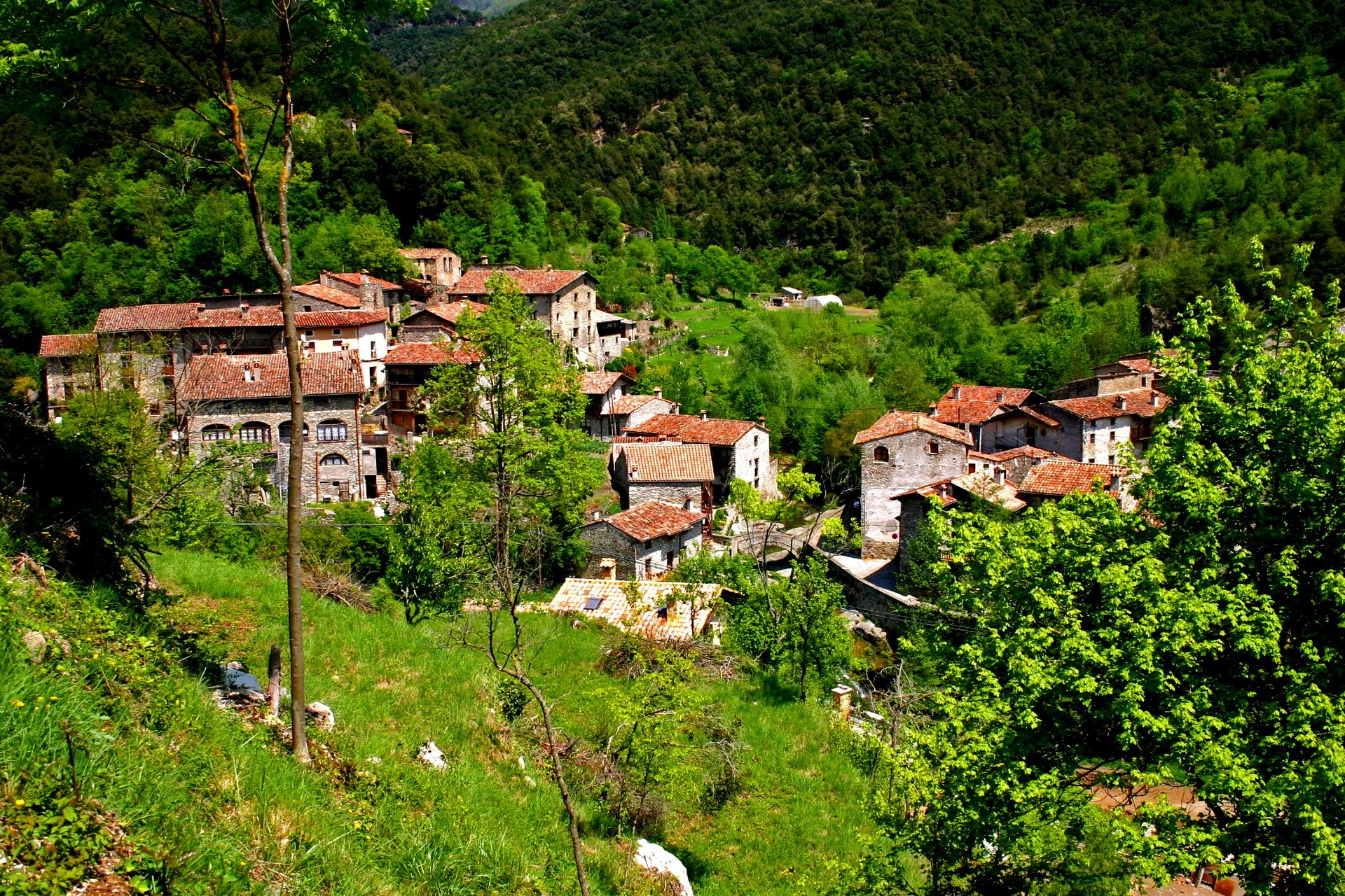 Village nestled in a green mountain valley HD Wallpaper