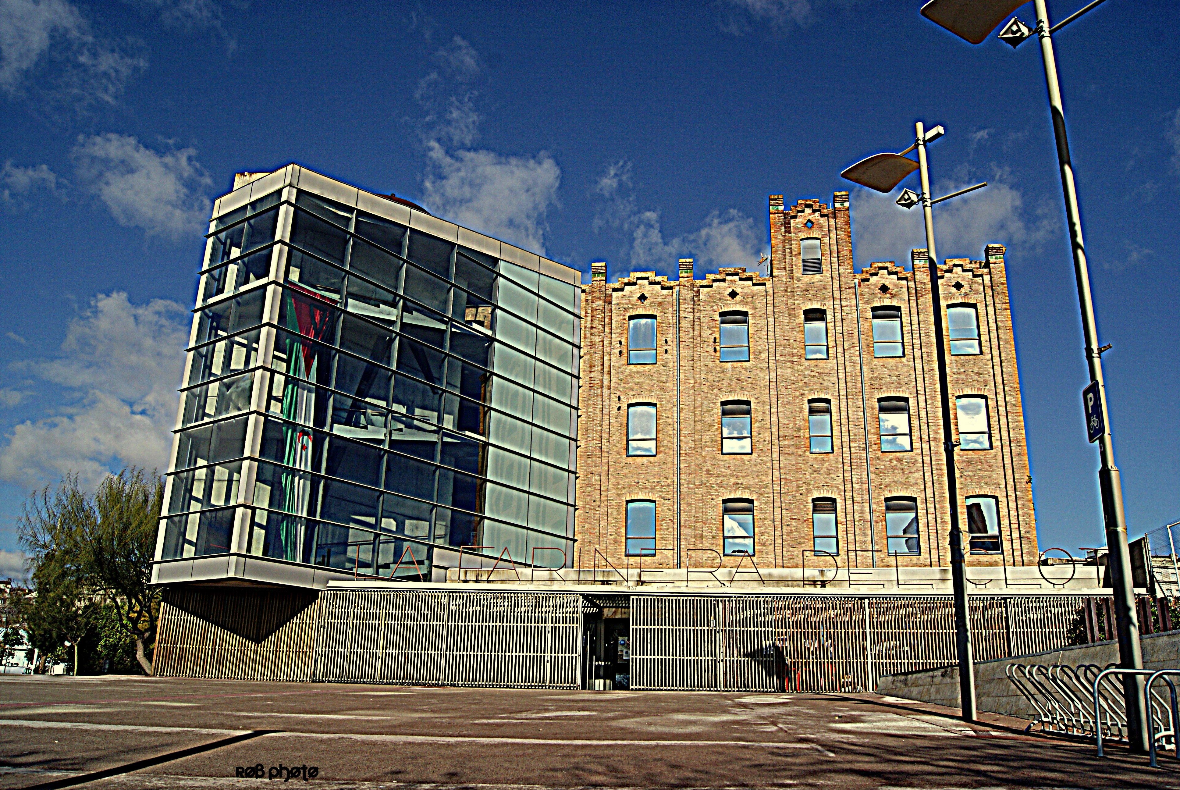 Modern glass building next to old brick building in Spain HD Wallpaper