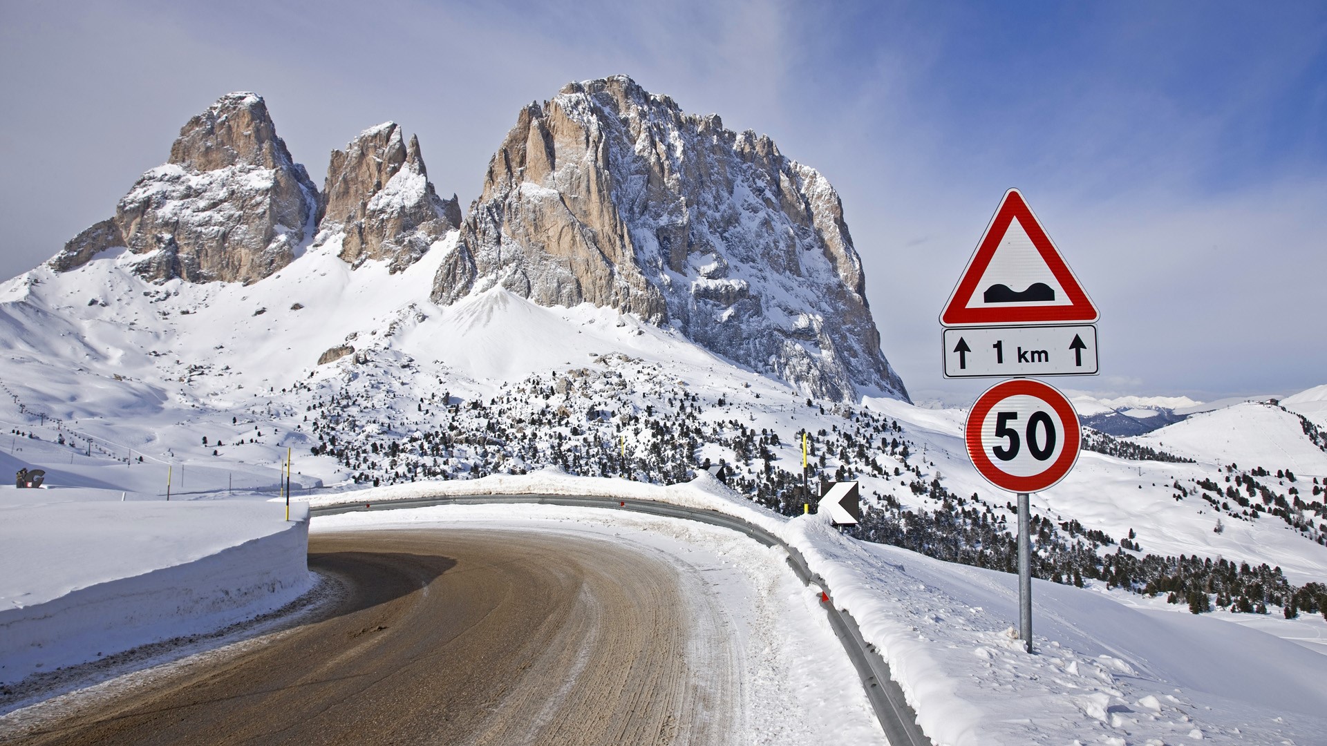 Snowy mountain road with speed limit sign in Italy HD Wallpaper