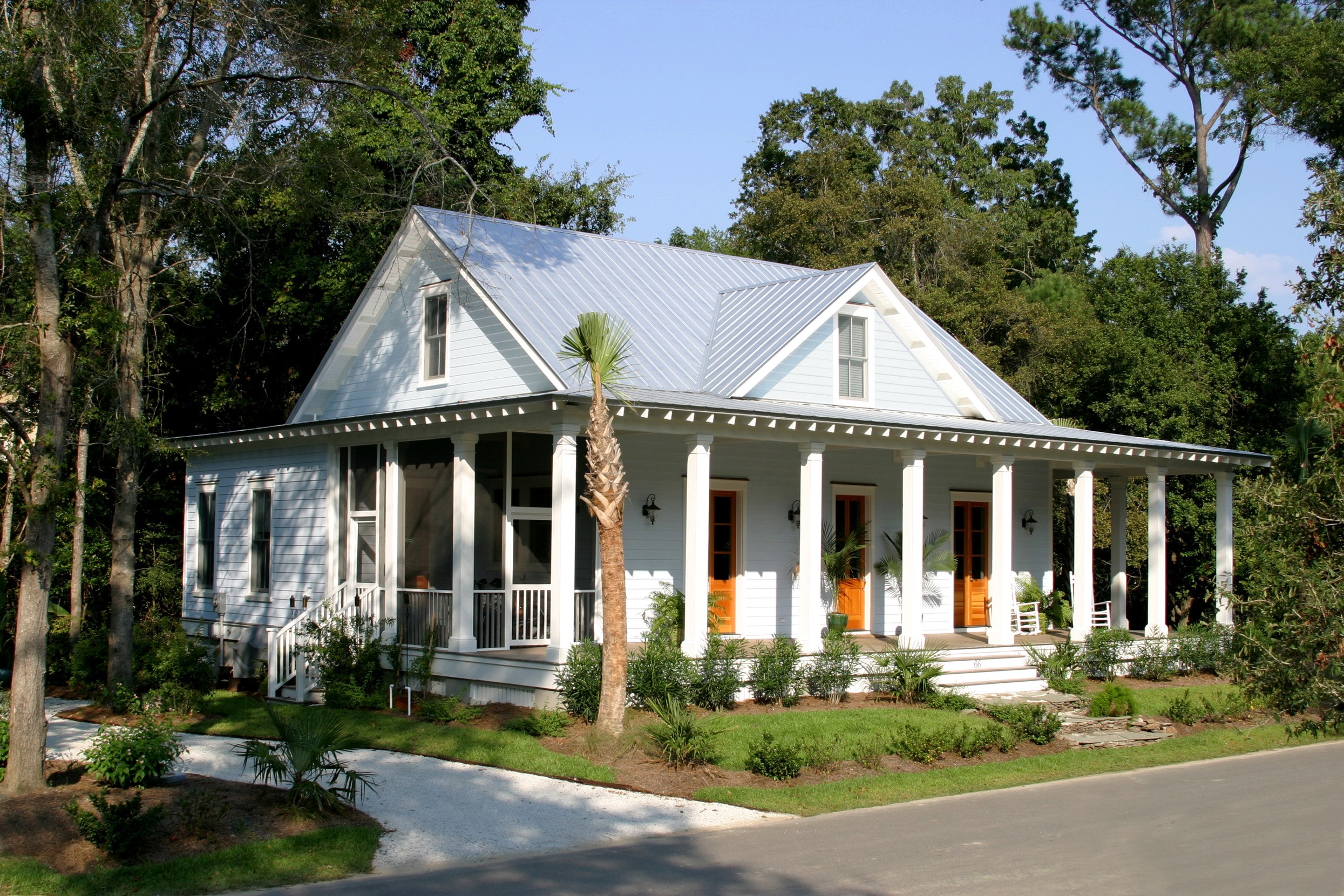 Light blue house with a wrap-around porch in a wooded area HD Wallpaper
