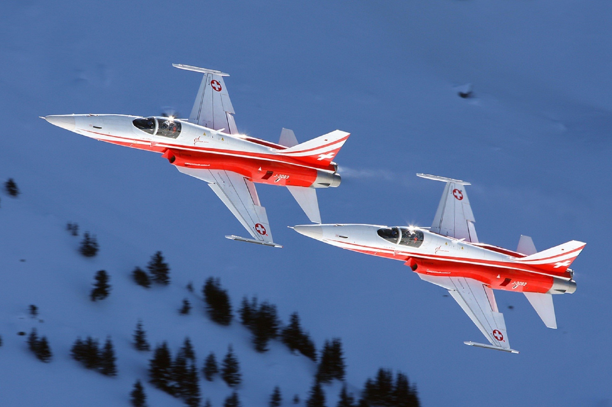 Two Swiss Air Force F-5E Tiger II jets flying over snowy mountains HD Wallpaper