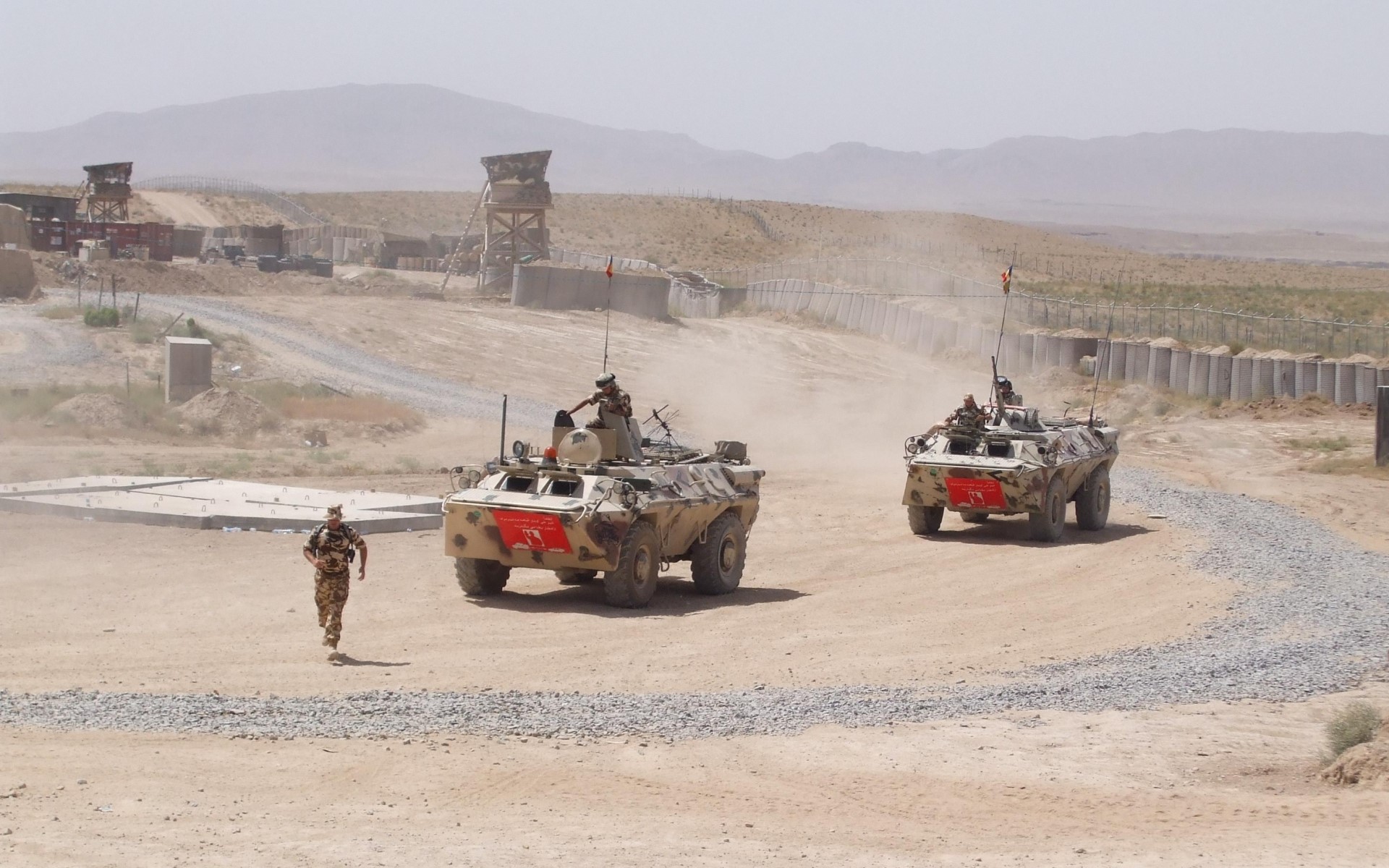 Soldiers and armored vehicles in a desert military base HD Wallpaper