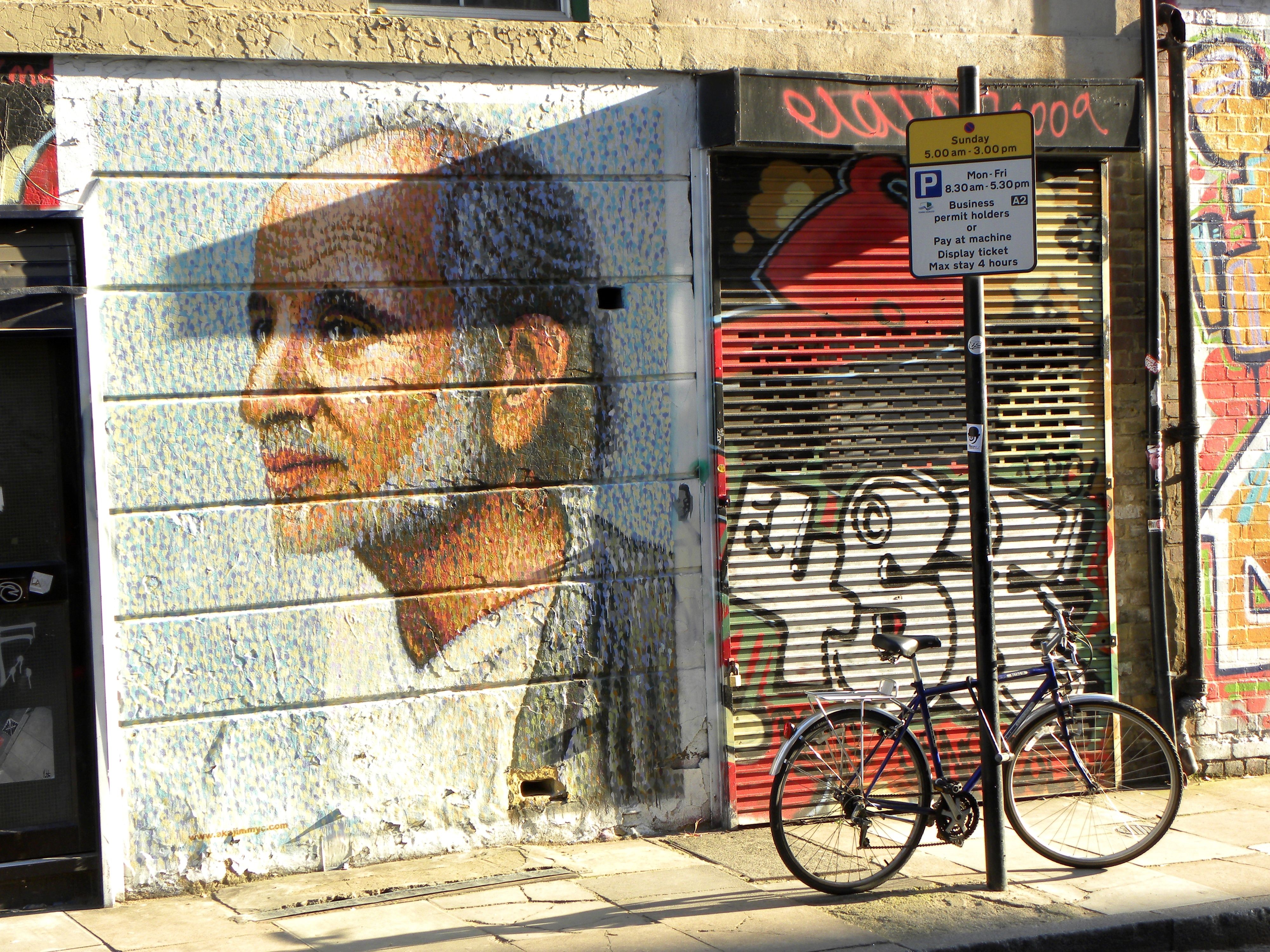 Graffiti and a portrait mural on a building HD Wallpaper