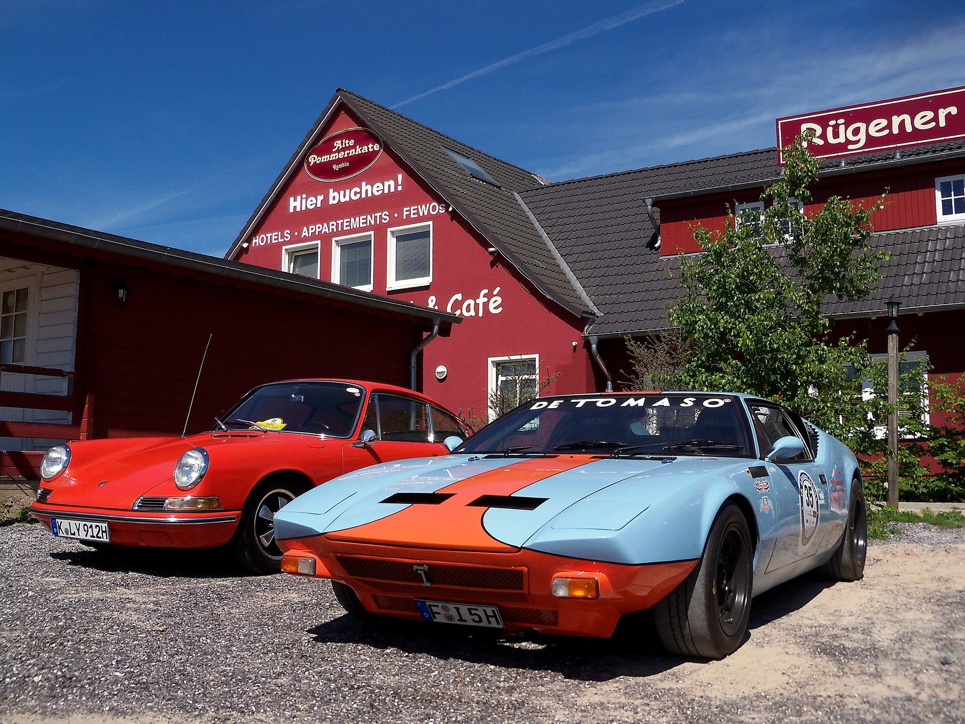De Tomaso and Porsche cars parked outside a building HD Wallpaper