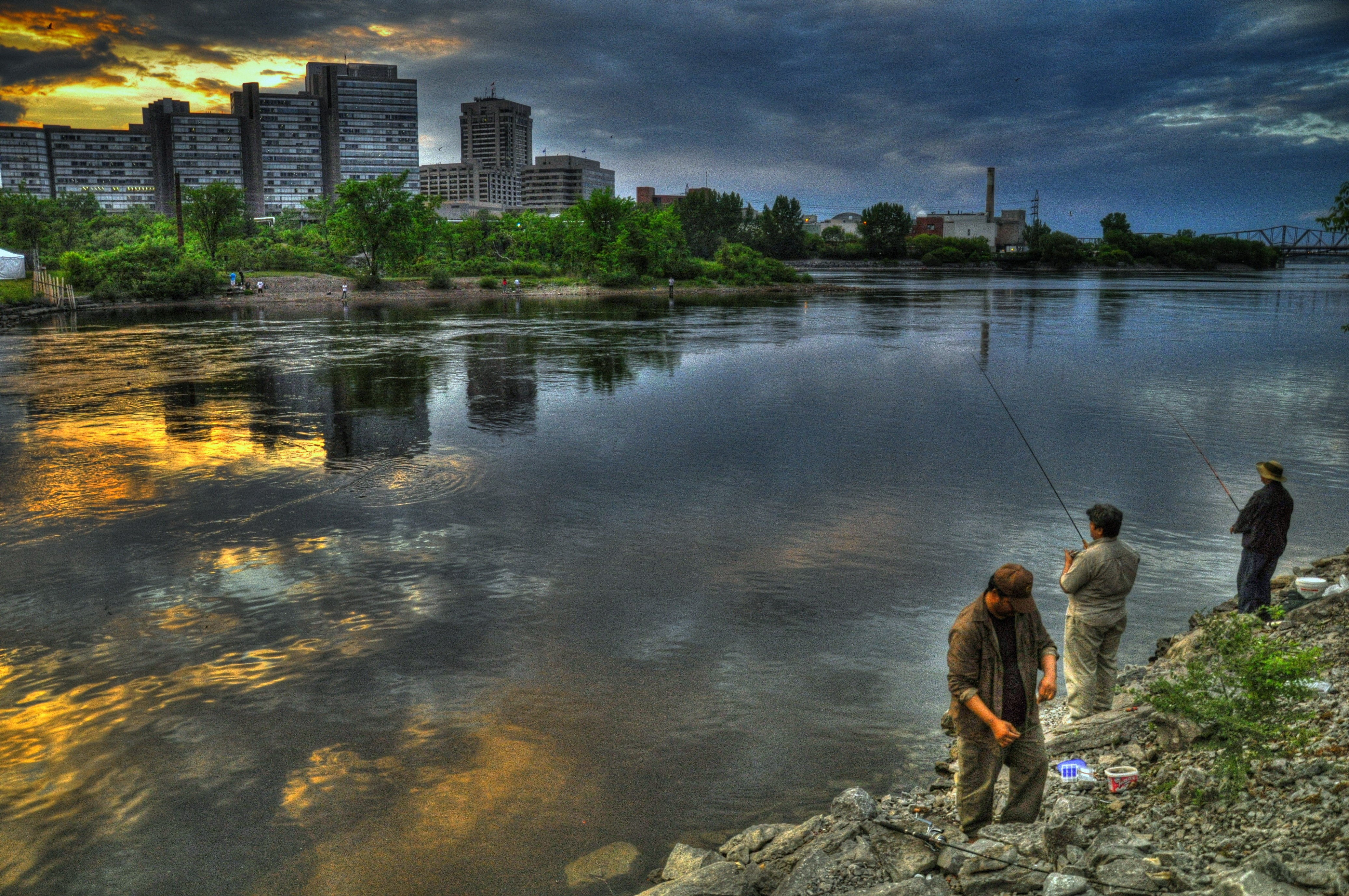 People fishing on a river with city skyline HD Wallpaper