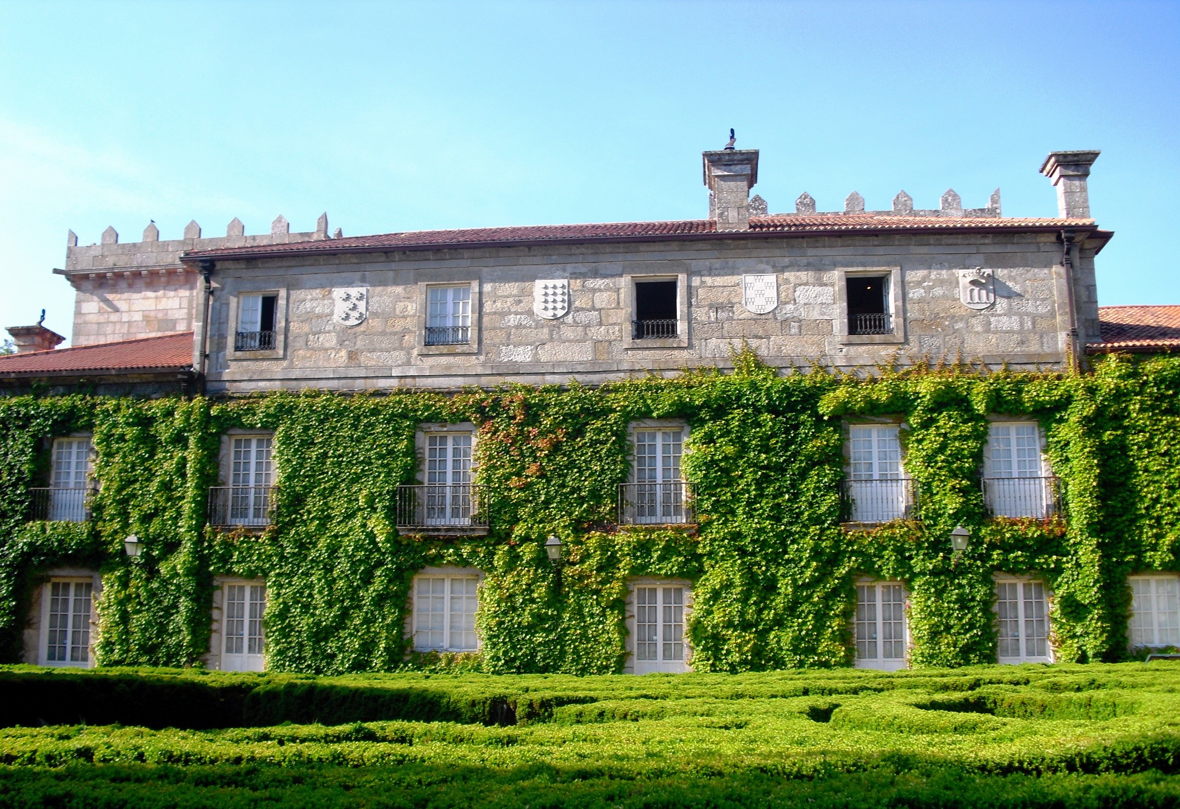Stone building covered in ivy with a formal garden HD Wallpaper