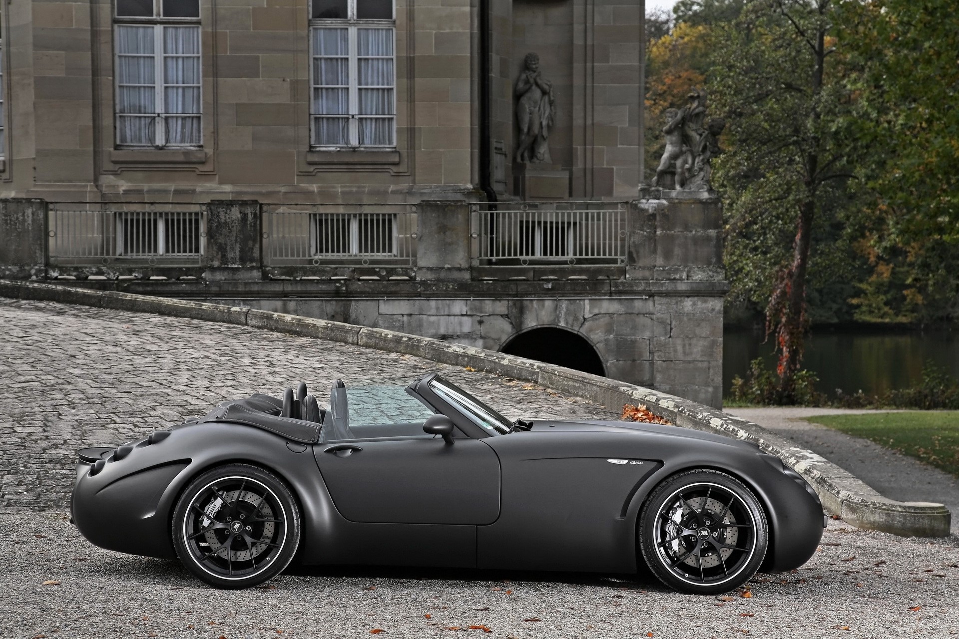 Matte black Wiesmann convertible sports car parked on cobblestone driveway HD Wallpaper