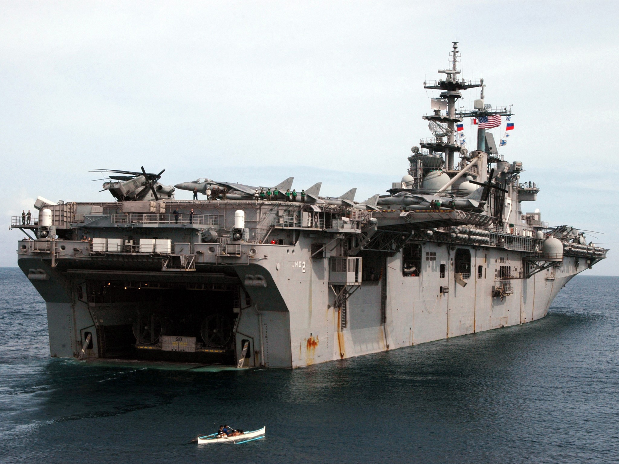 Amphibious assault ship with aircraft and a small boat HD Wallpaper