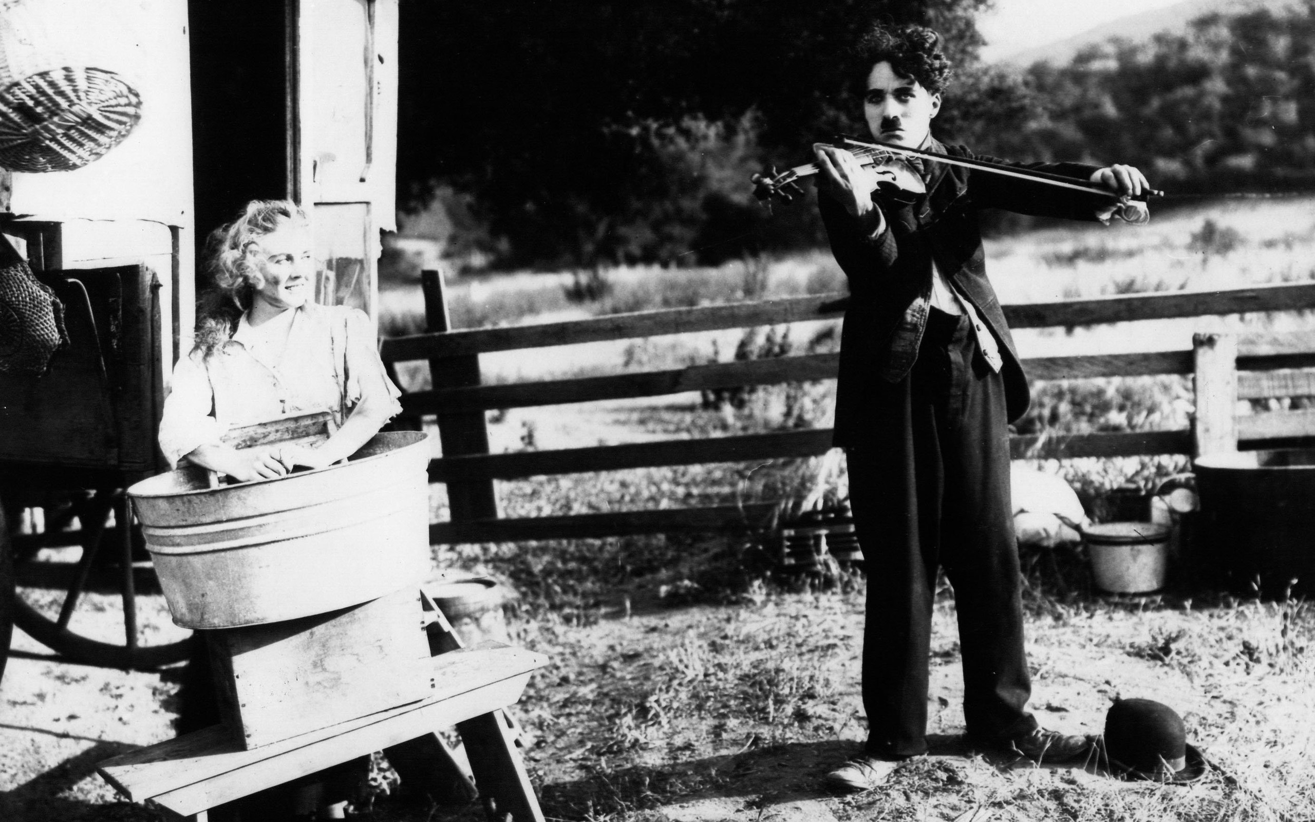 Charlie Chaplin playing violin for a woman in a tub HD Wallpaper