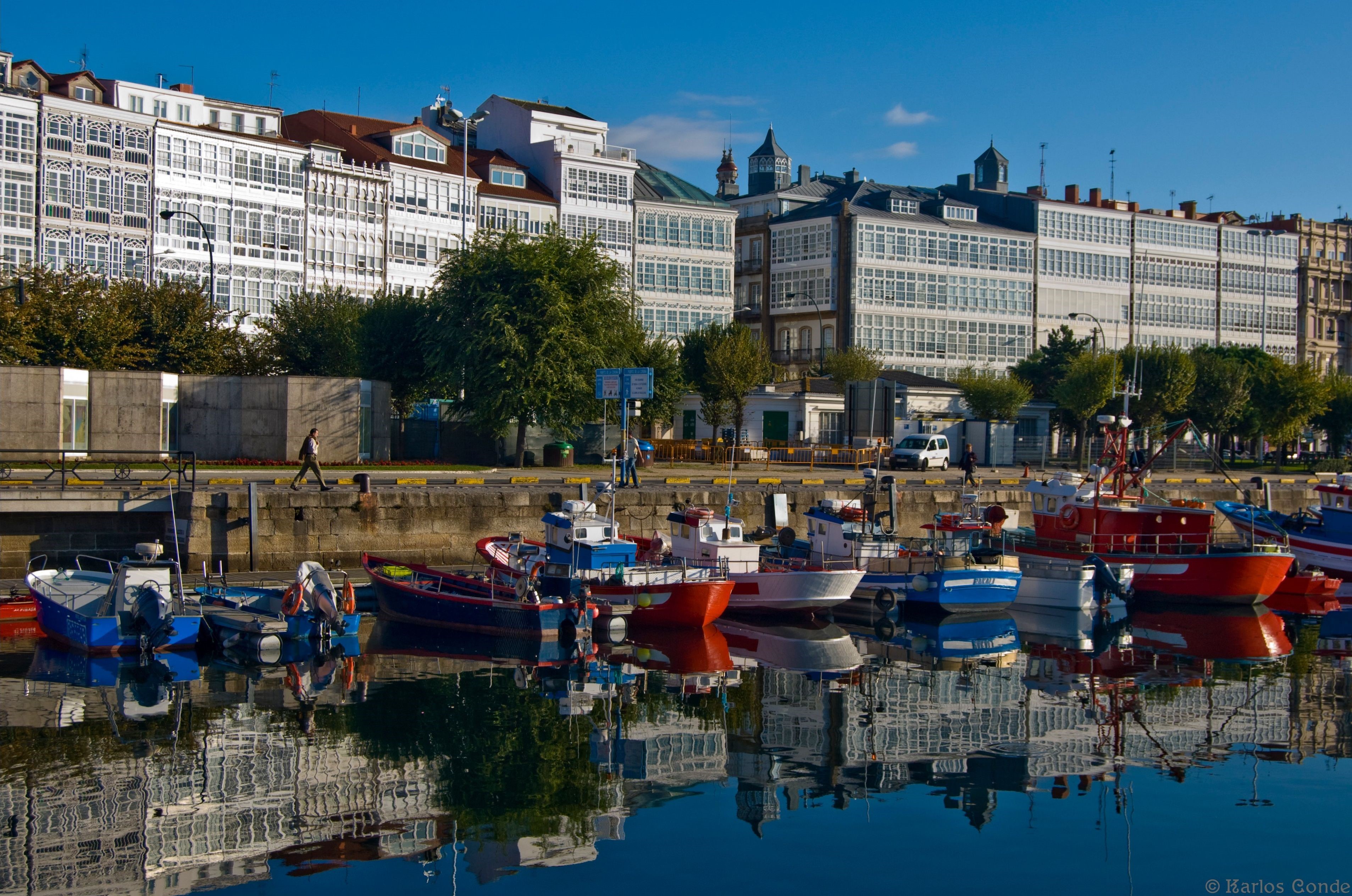Boats docked in a harbor with buildings in the background, Spain HD Wallpaper