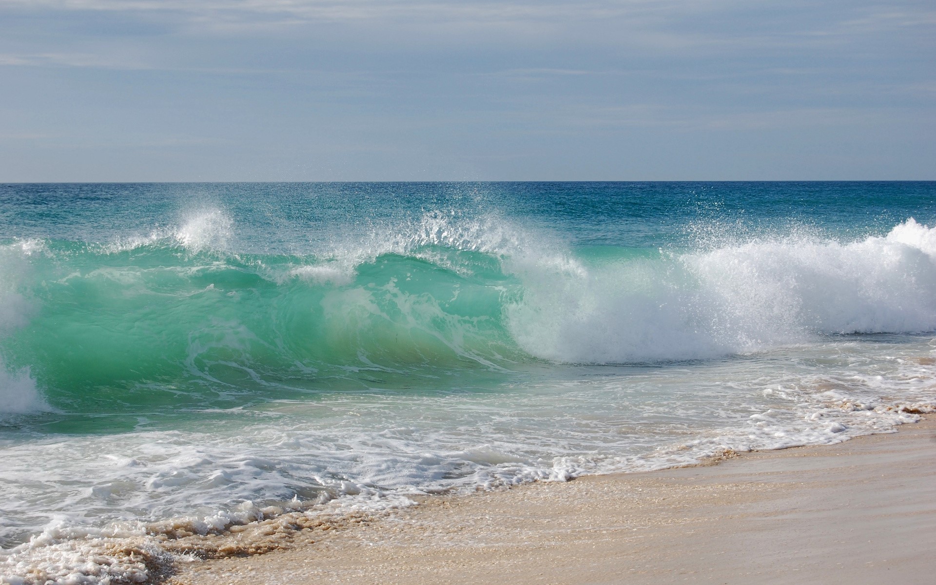 Turquoise wave crashing on a sandy beach HD Wallpaper