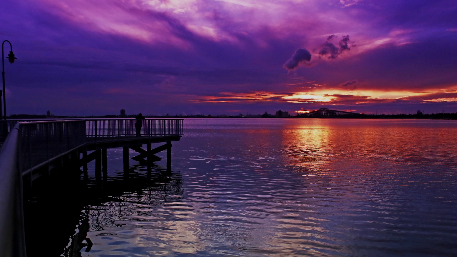 Person on pier watching colorful sunset over water HD Wallpaper