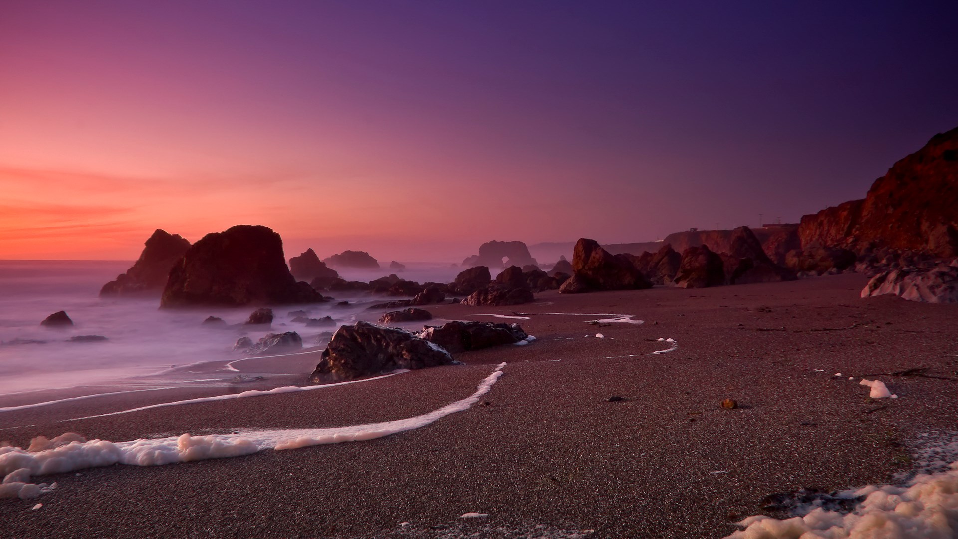 Rocky beach at sunset with purple and orange sky HD Wallpaper