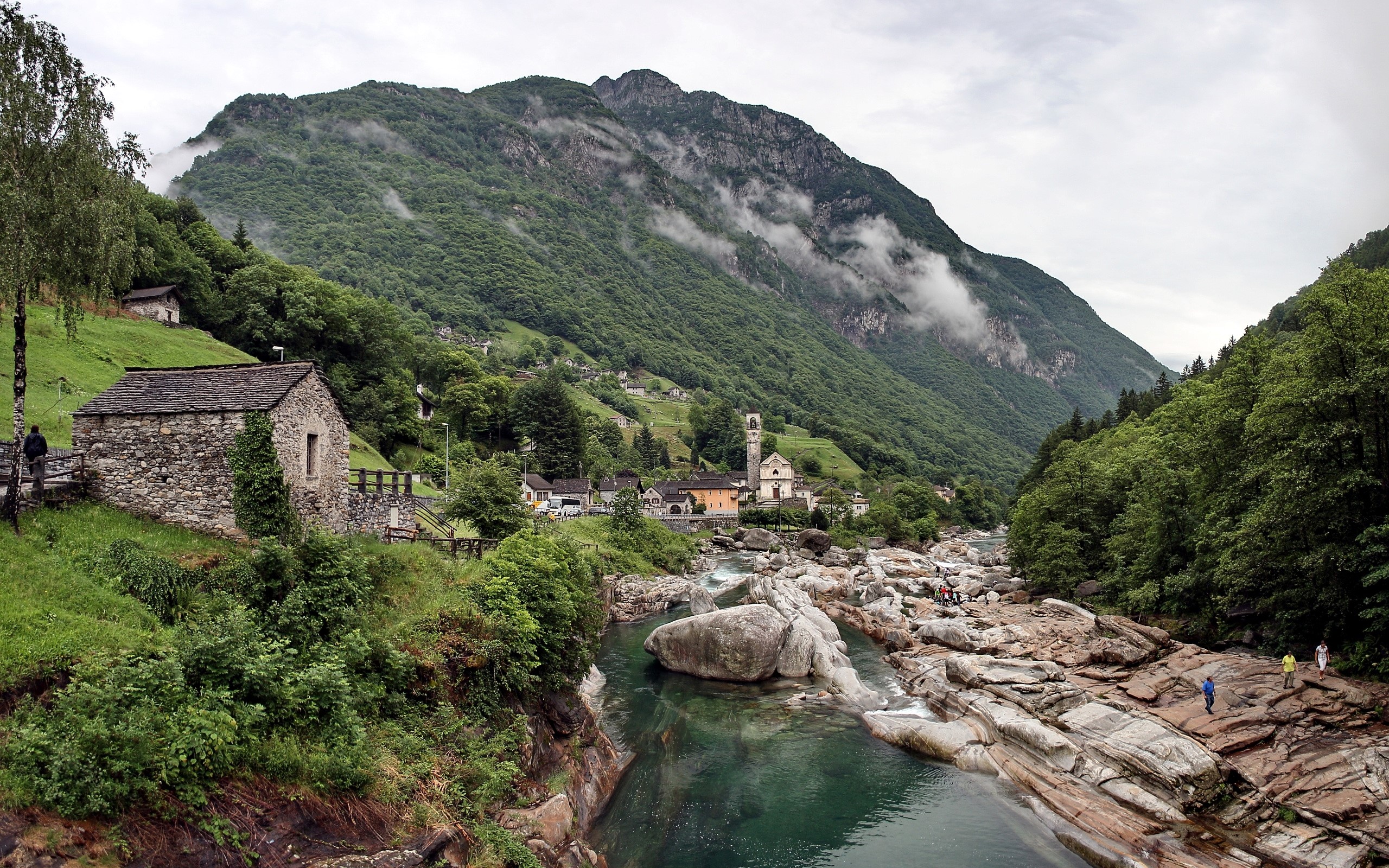 Stone house and church in a mountain valley with a river HD Wallpaper